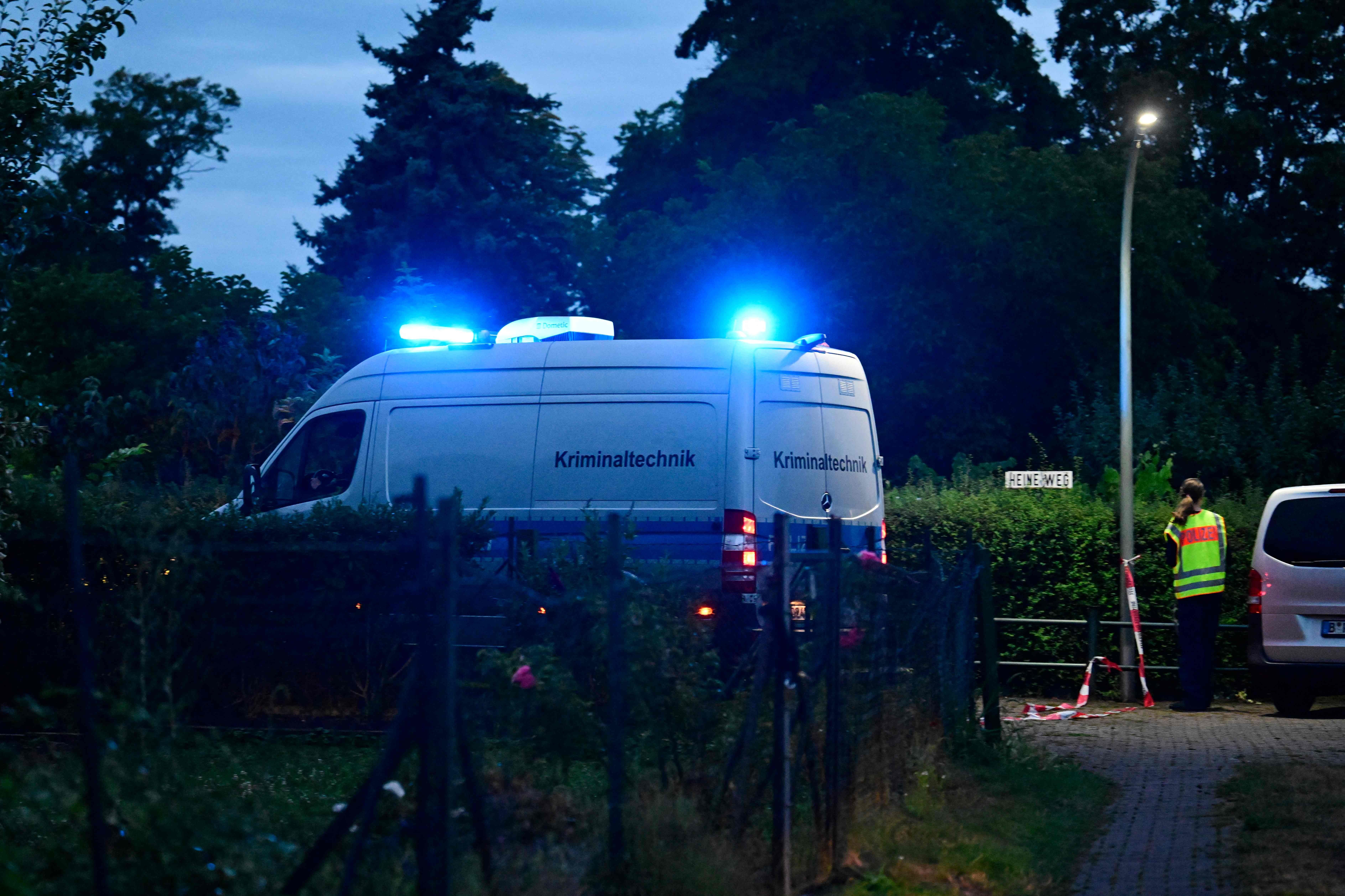 Ein Polizeiwagen der Kriminaltechnik fährt am Sonntag in einer Kleingartenanlage im westlichen Berliner Bezirk Spandau in Richtung des Tatorts, in einem Gartenbereich nahe der Stelle, an der der Hauptverdächtige des tödlichen Anschlags der vergangenen Nacht in der Nähe der Berliner Pride-Parade erschossen wurde.