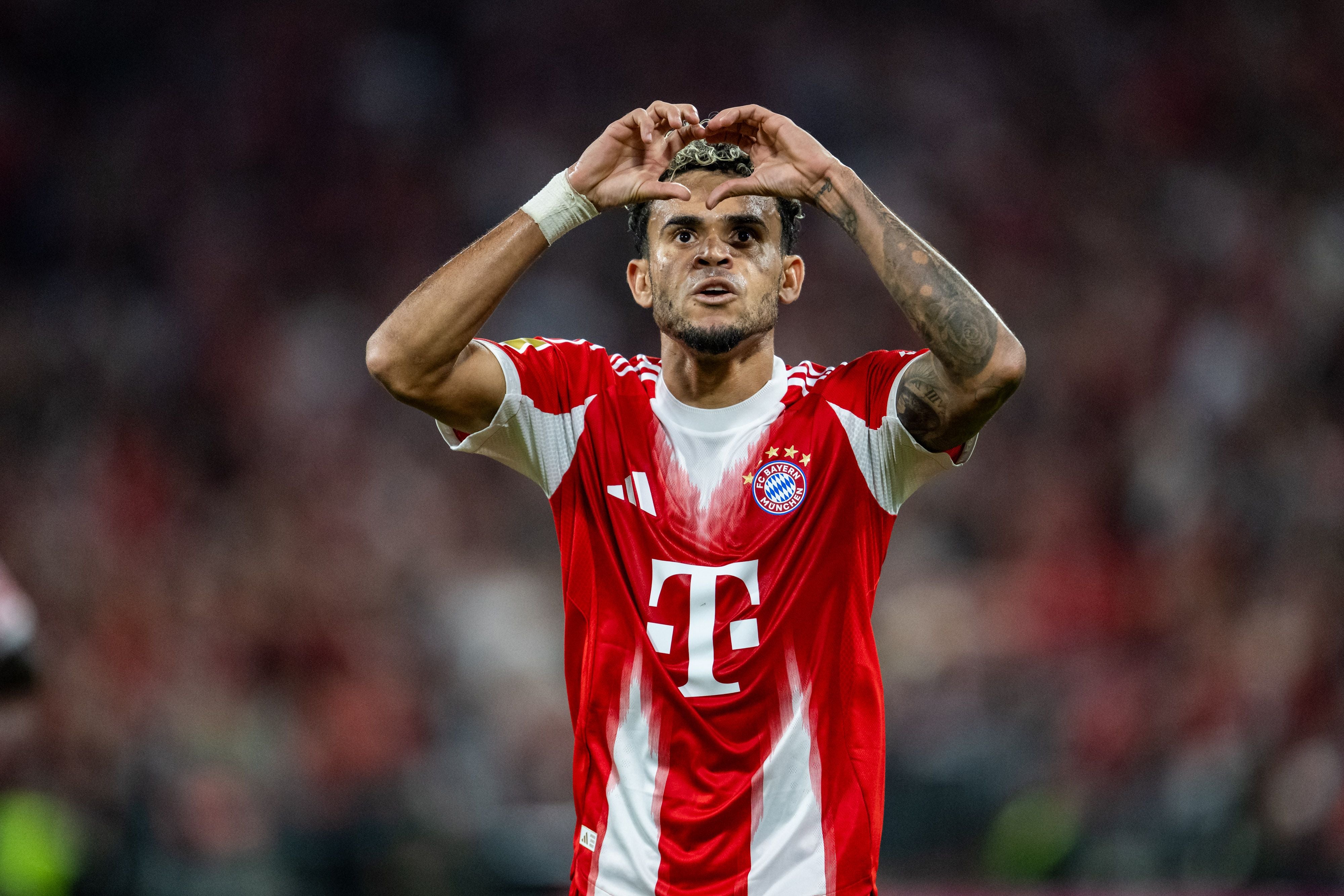 Ein Fußballspieler im Bayern-Trikot jubelt mit einer Handgeste auf dem Spielfeld.