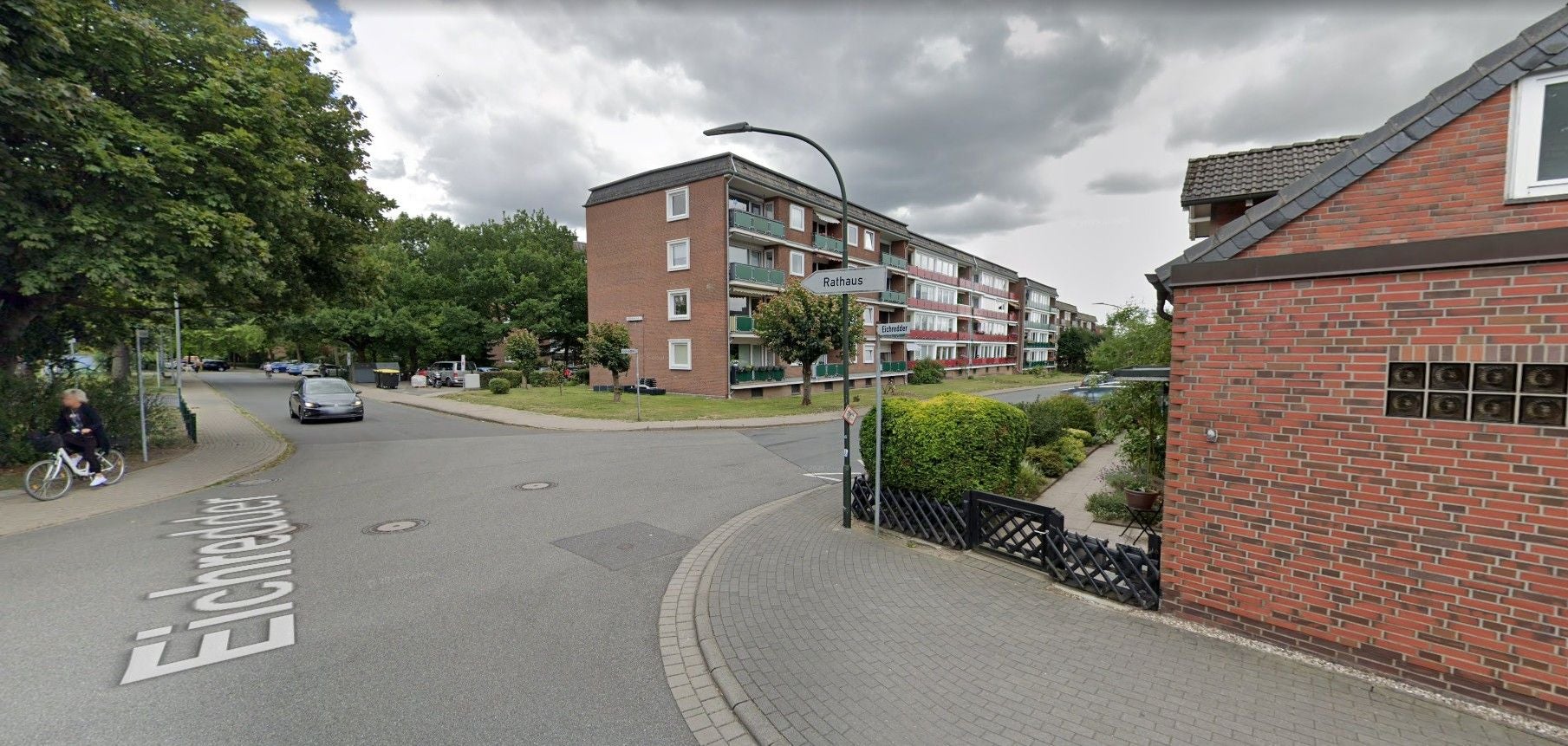 Straßenecke mit Wohnhäusern, Straßenschildern und Bäumen in Oststeinbek, Schleswig-Holstein.