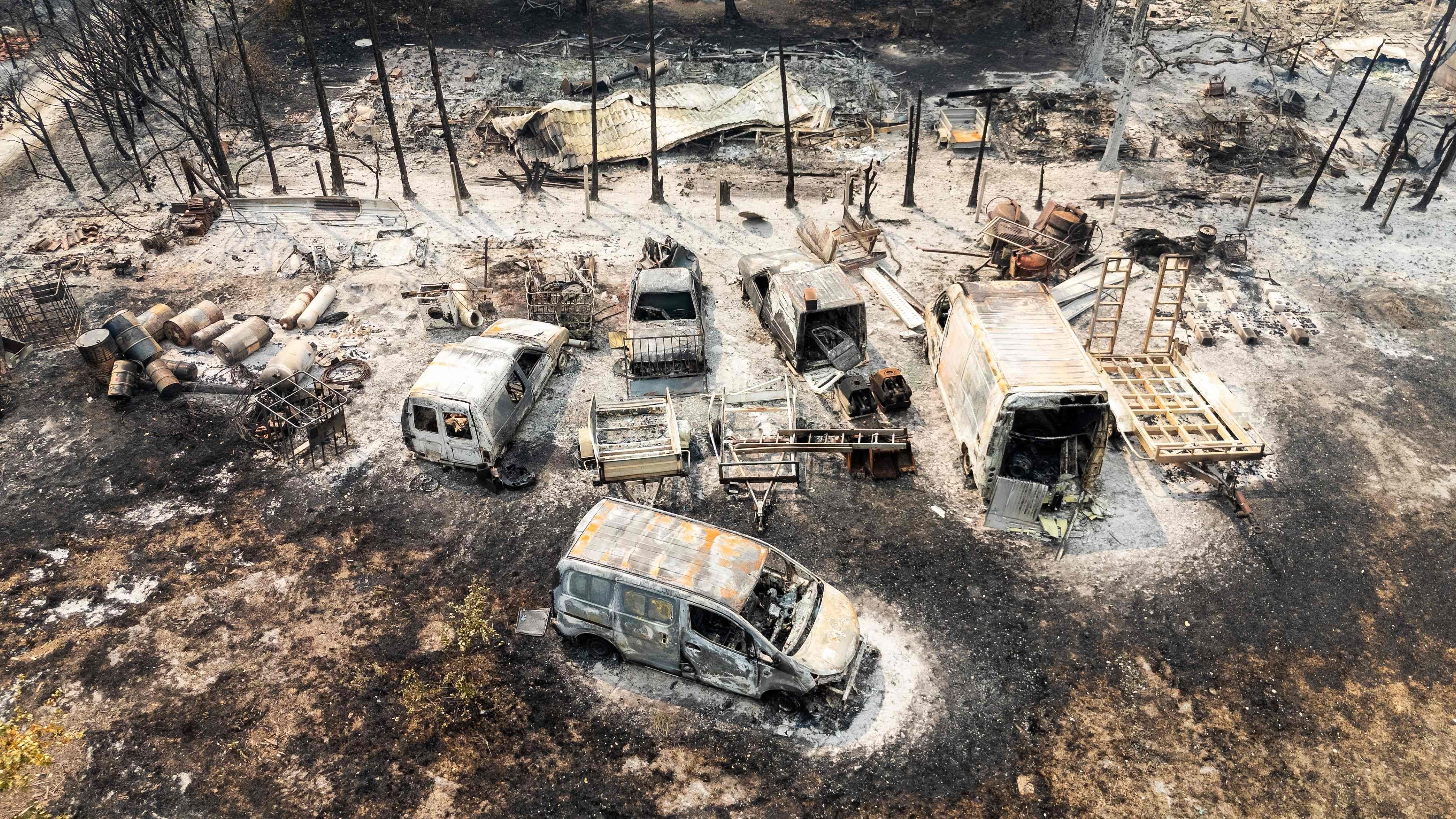 Luftaufnahme von ausgebrannten Autos und zerstörtem Gelände nach einem Waldbrand in Le Porge, Frankreich.