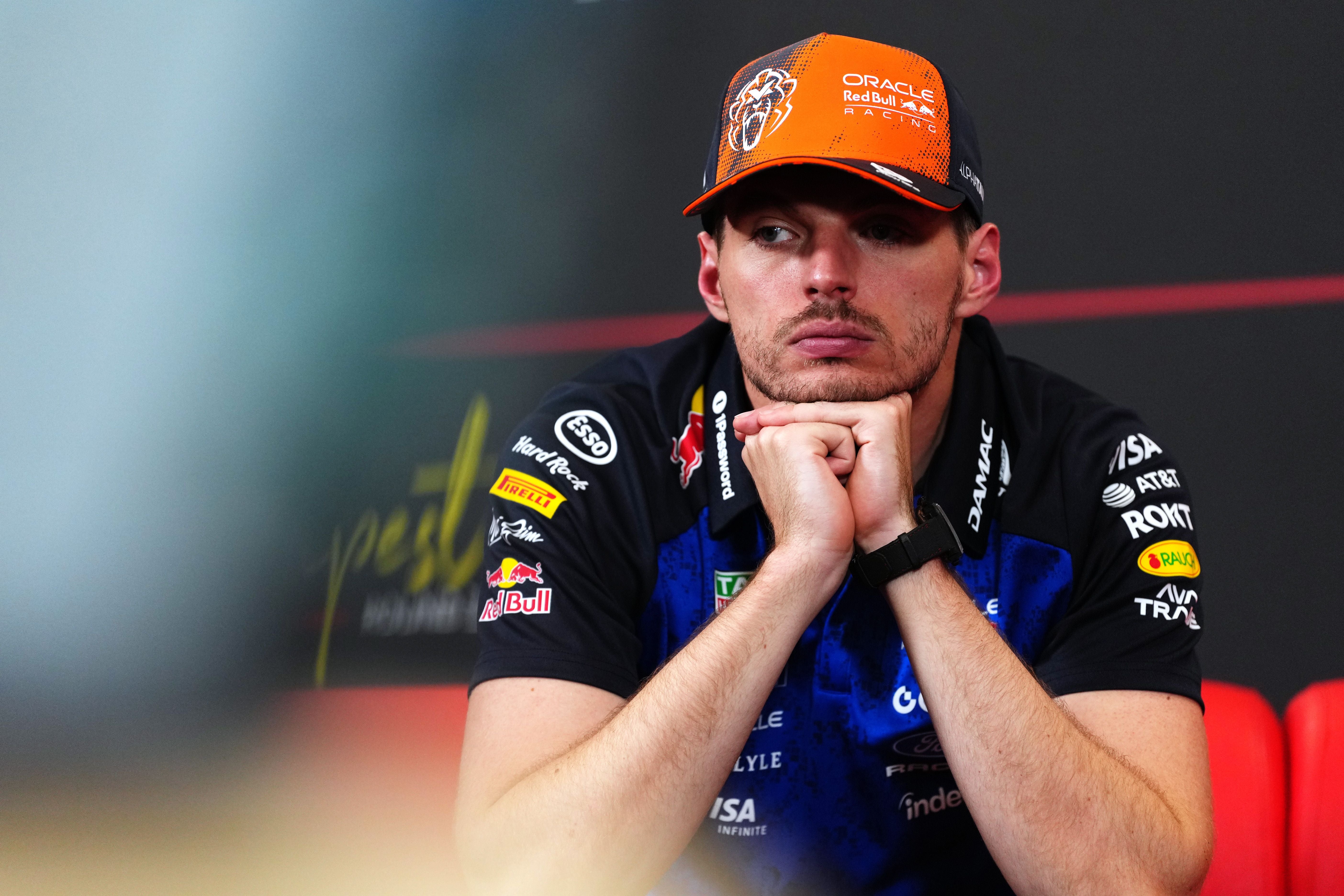 Ein Mann im Red Bull Racing Outfit sitzt mit den Händen unter dem Kinn in einer Pressekonferenz.