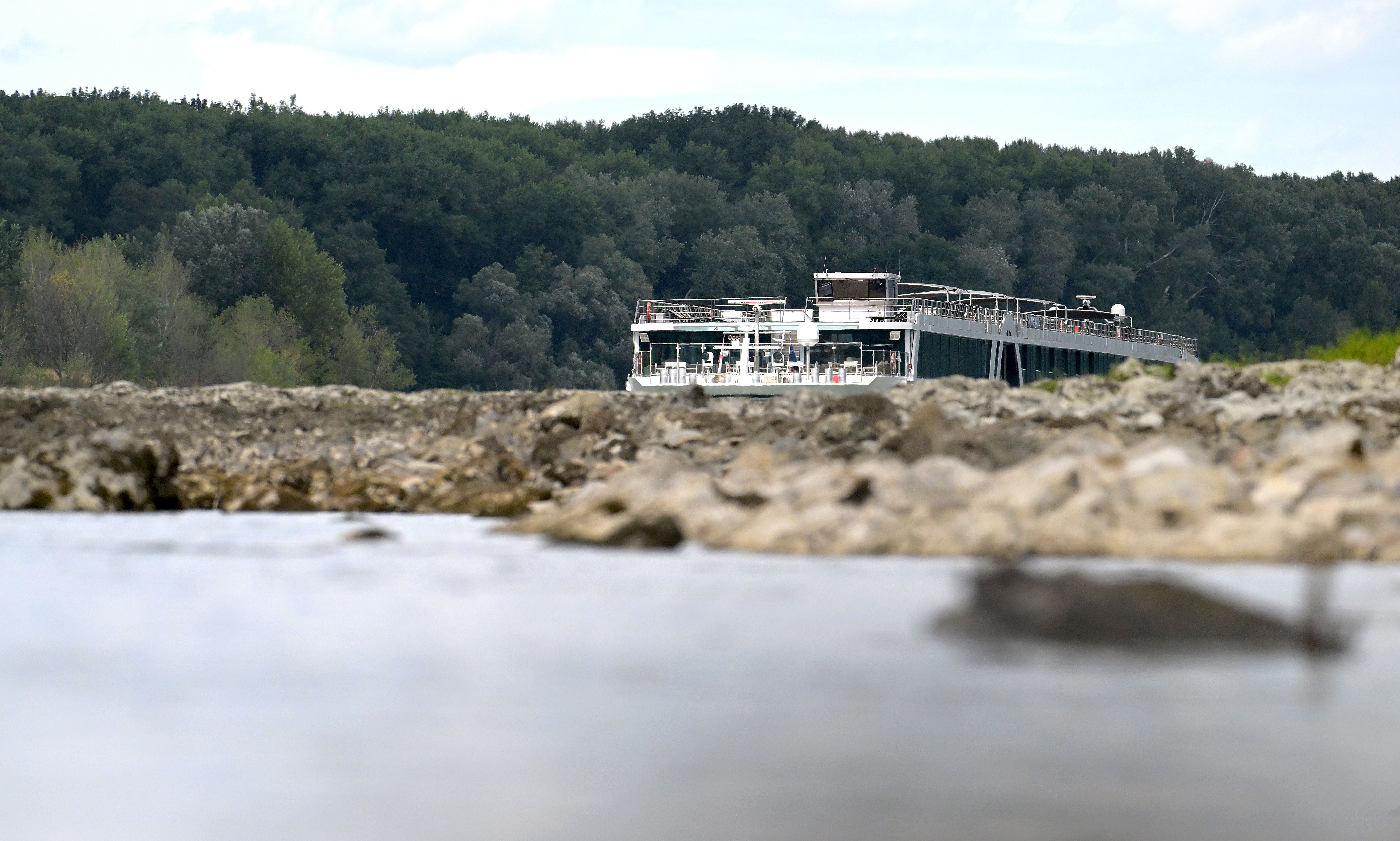 Ein Ausflugsschiff fährt bei niedrigem Wasserstand auf der Donau nahe Hainburg, umgeben von Bäumen.