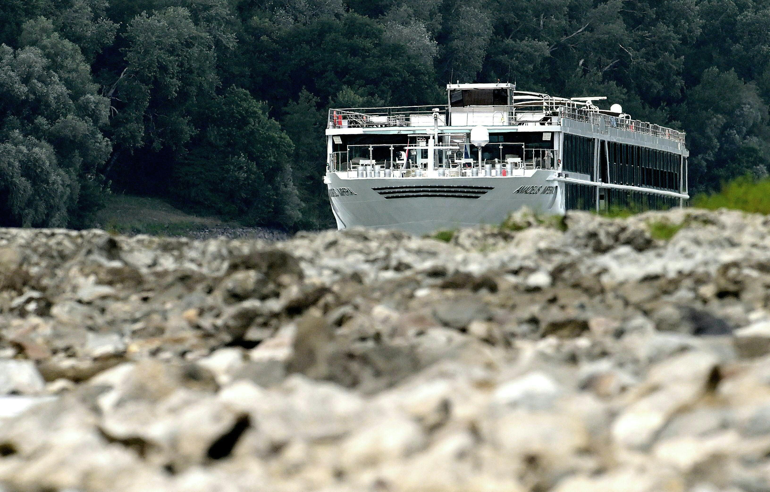 Ein Ausflugsschiff fährt bei niedrigem Wasserstand auf der Donau bei Hainburg, im Vordergrund Steine.