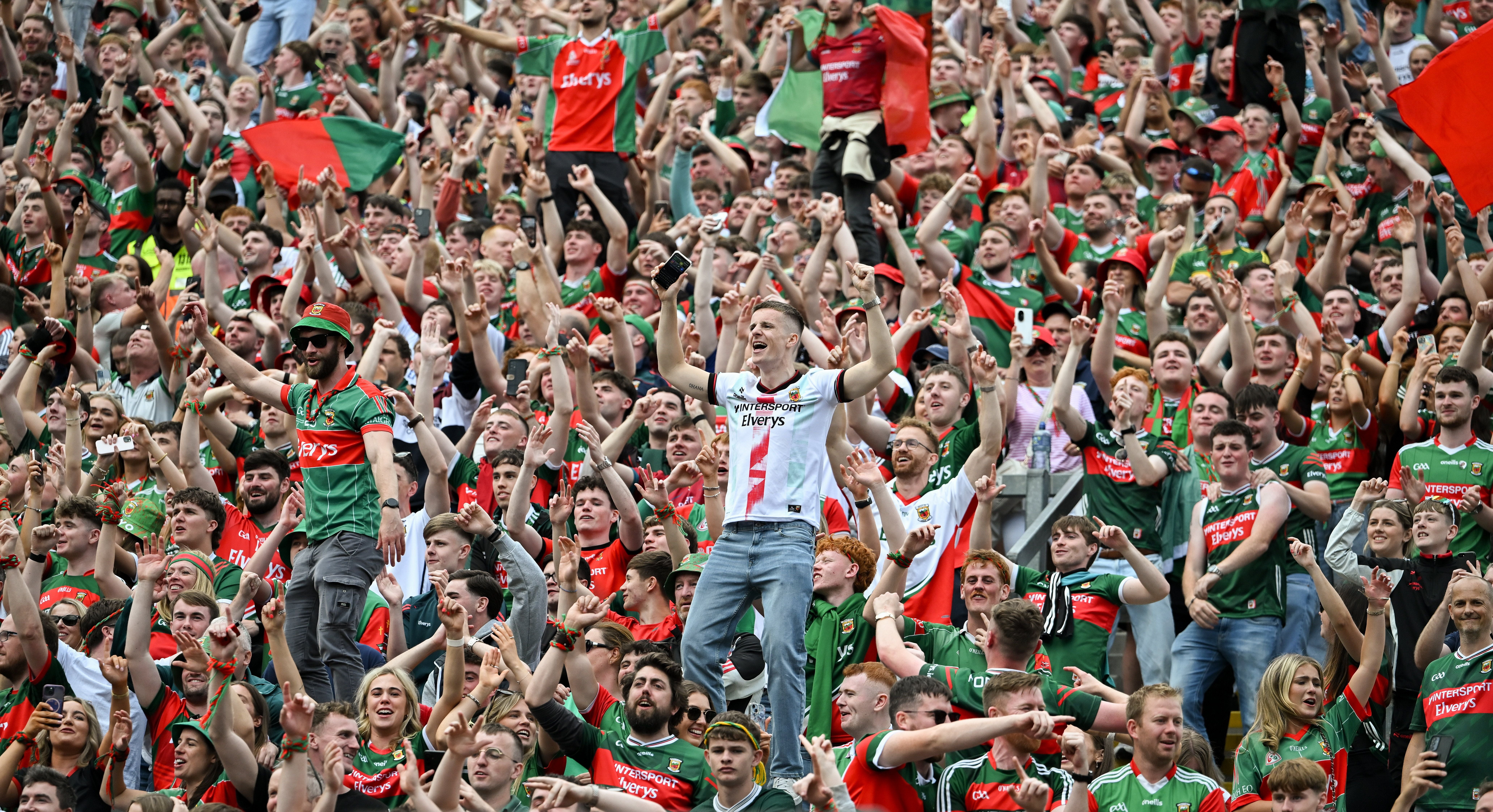 Jubelnde Mayo-Fans in grün-roten Trikots feiern im vollbesetzten Stadion.