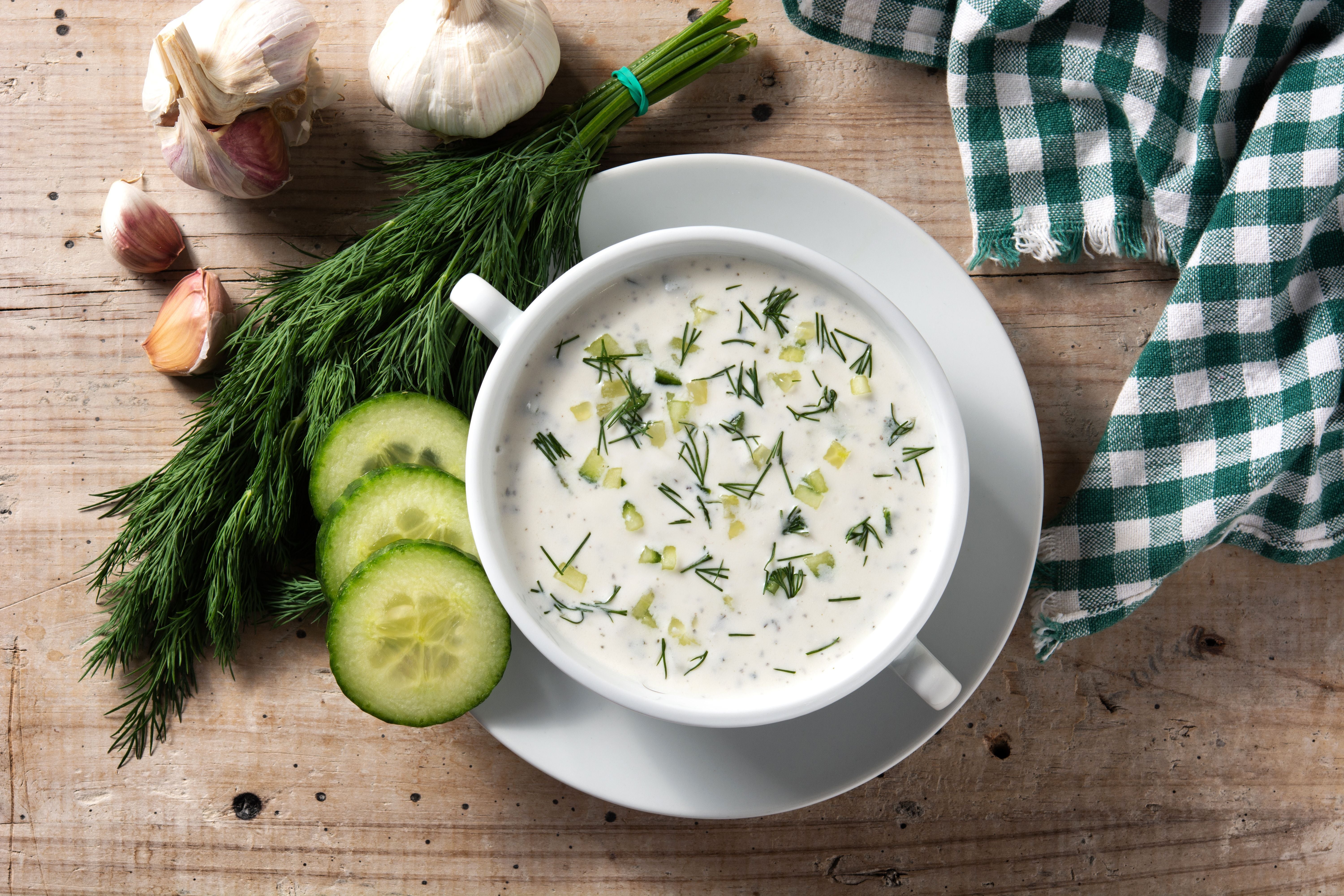 Bulgarische Tarator-Kaltschale mit Gurke, Dill und Knoblauch auf Holztisch serviert.