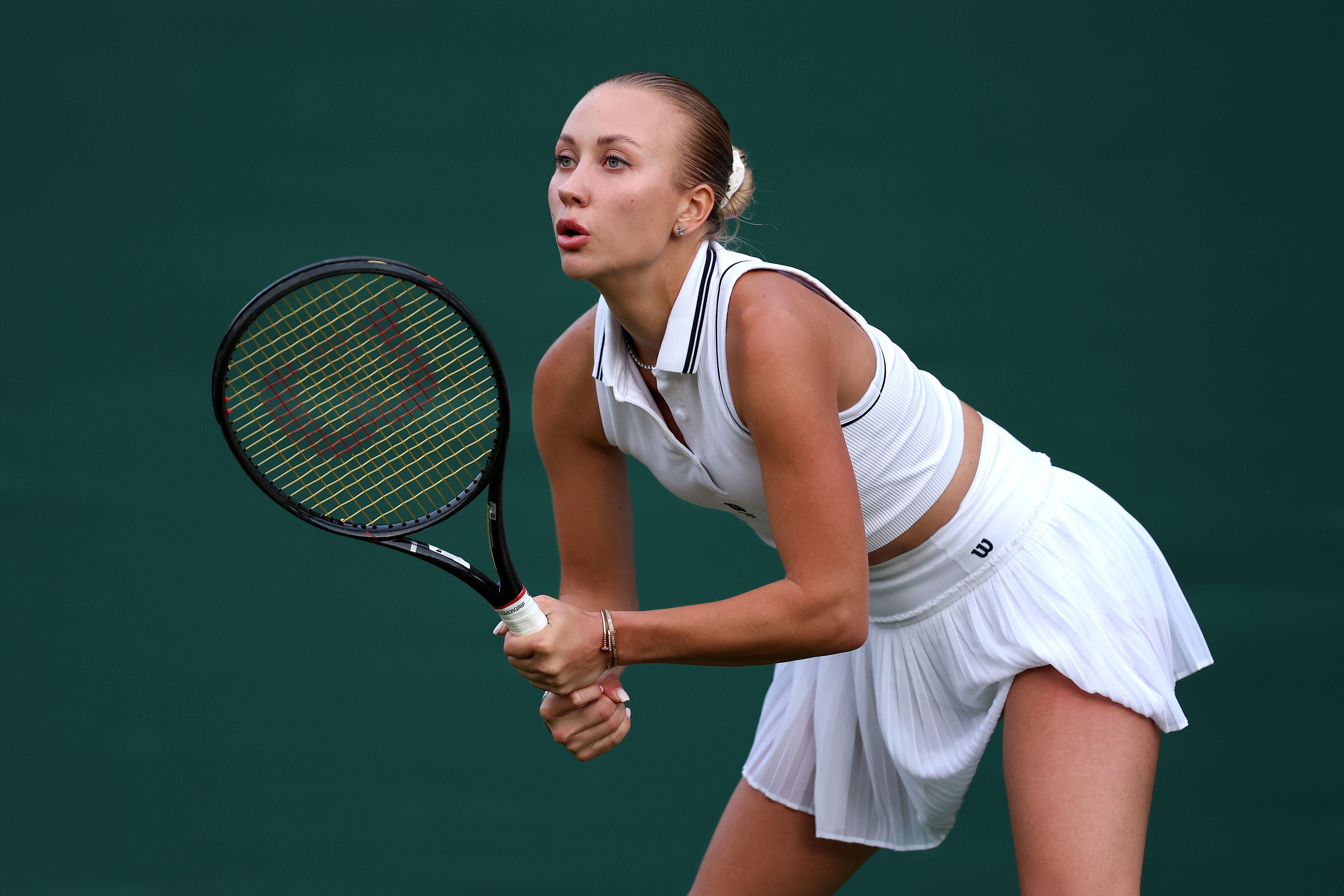 Tennisspielerin in weißer Kleidung bereitet sich auf einen Schlag bei einem Match vor.