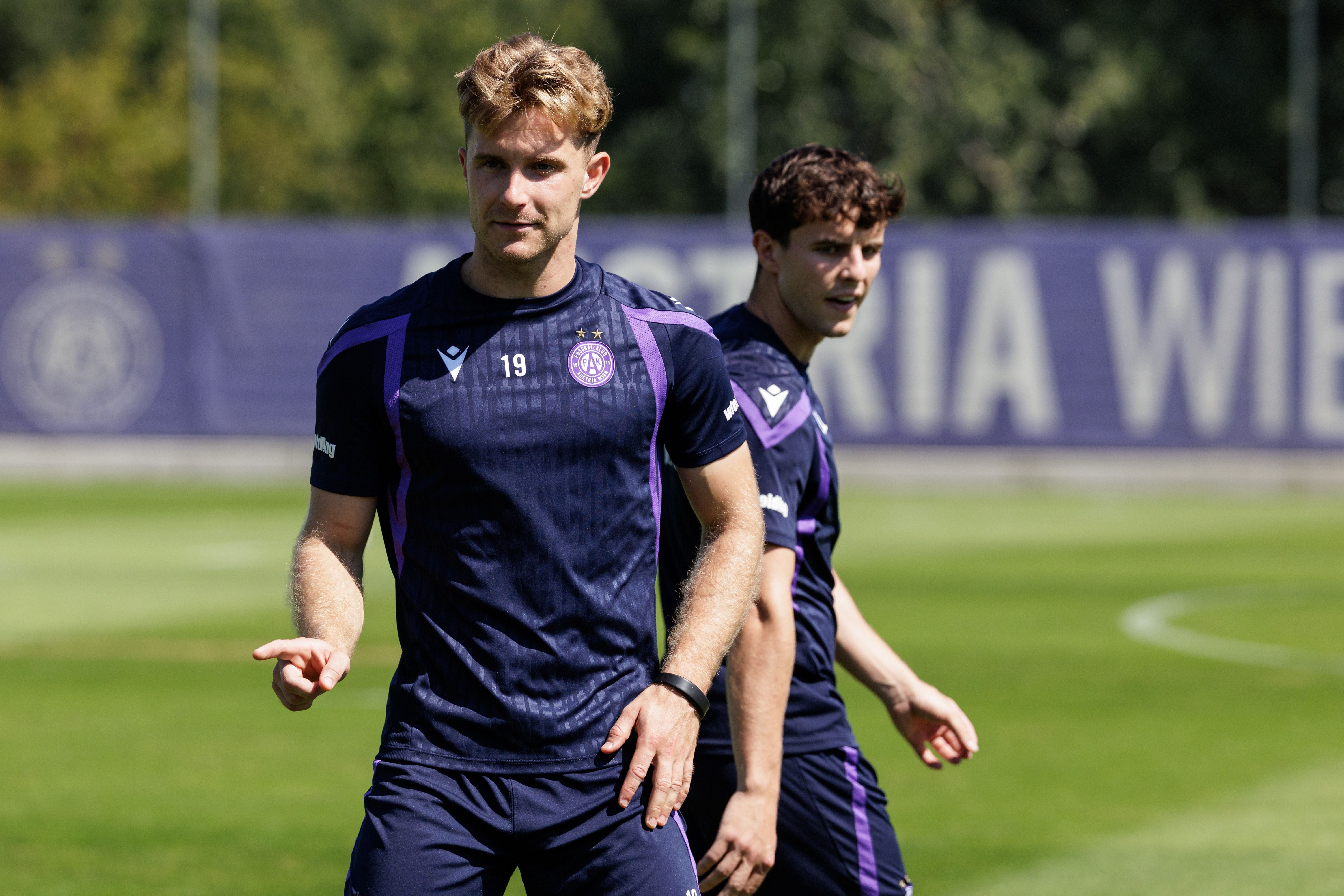 Zwei Fußballspieler von Austria Wien beim Training auf dem Rasen bei Sonnenschein.