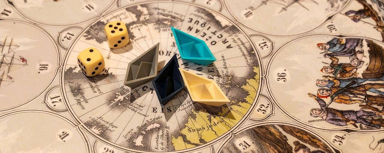 Vier bunte Spielfiguren und zwei Würfel auf einer historischen Weltkarte.