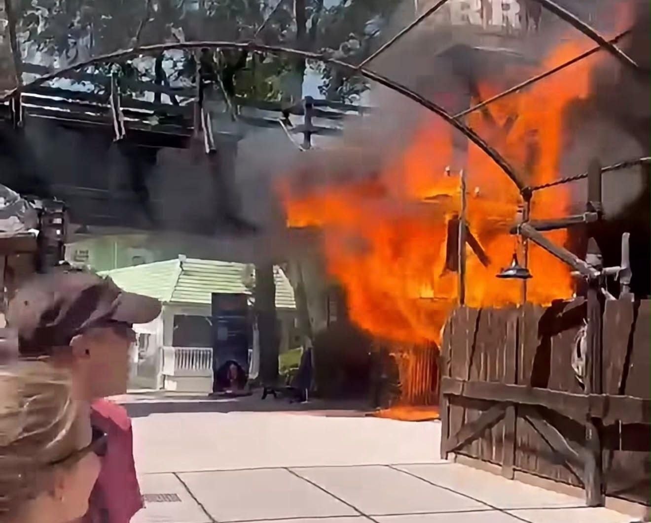 Großes Feuer brennt an einem Holzgebäude im Freizeitpark Gardaland, Menschen schauen zu.