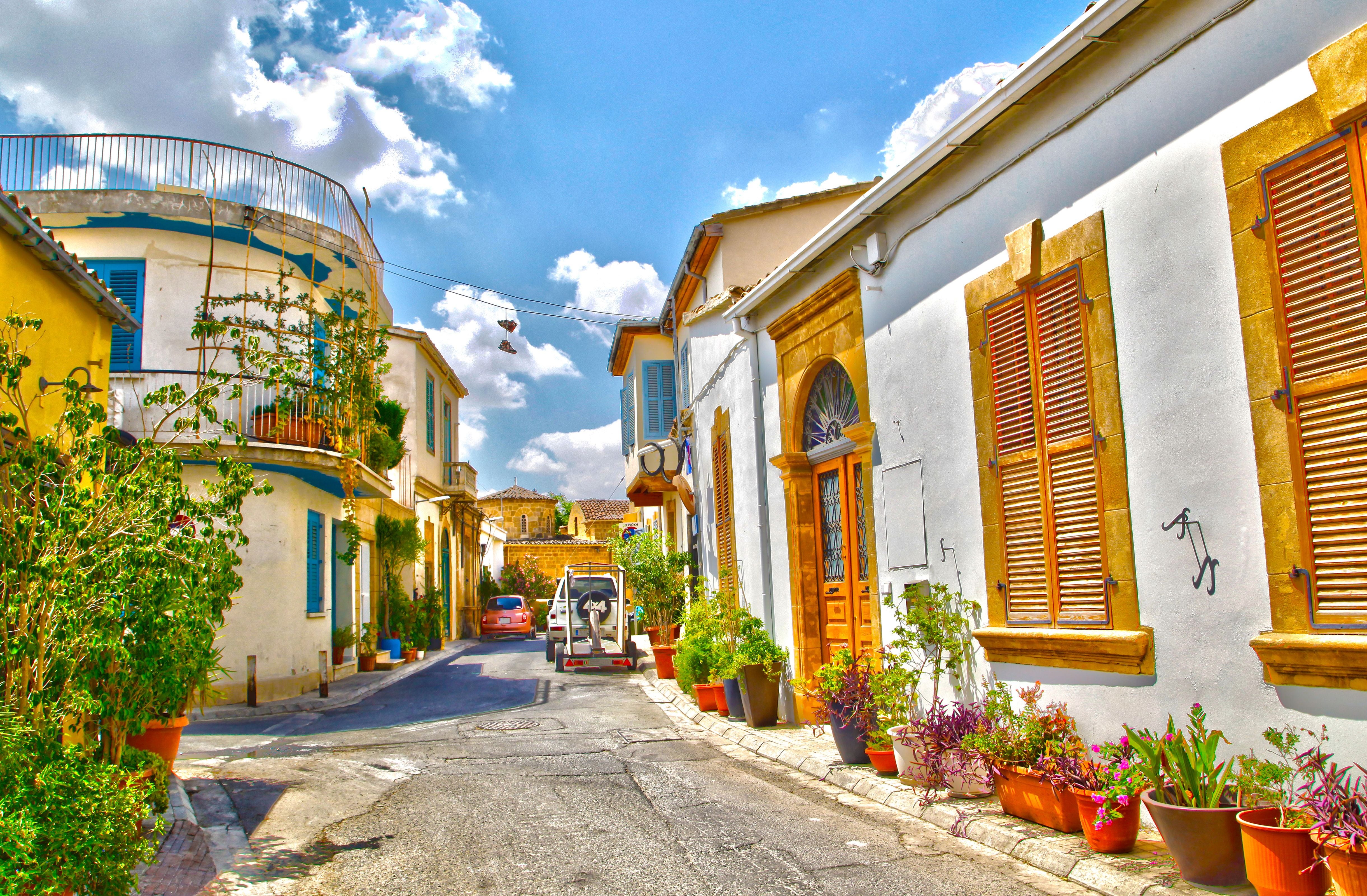 Bunte Gasse in Nikosia Altstadt mit Pflanzen, alten Häusern und blauem Himmel.