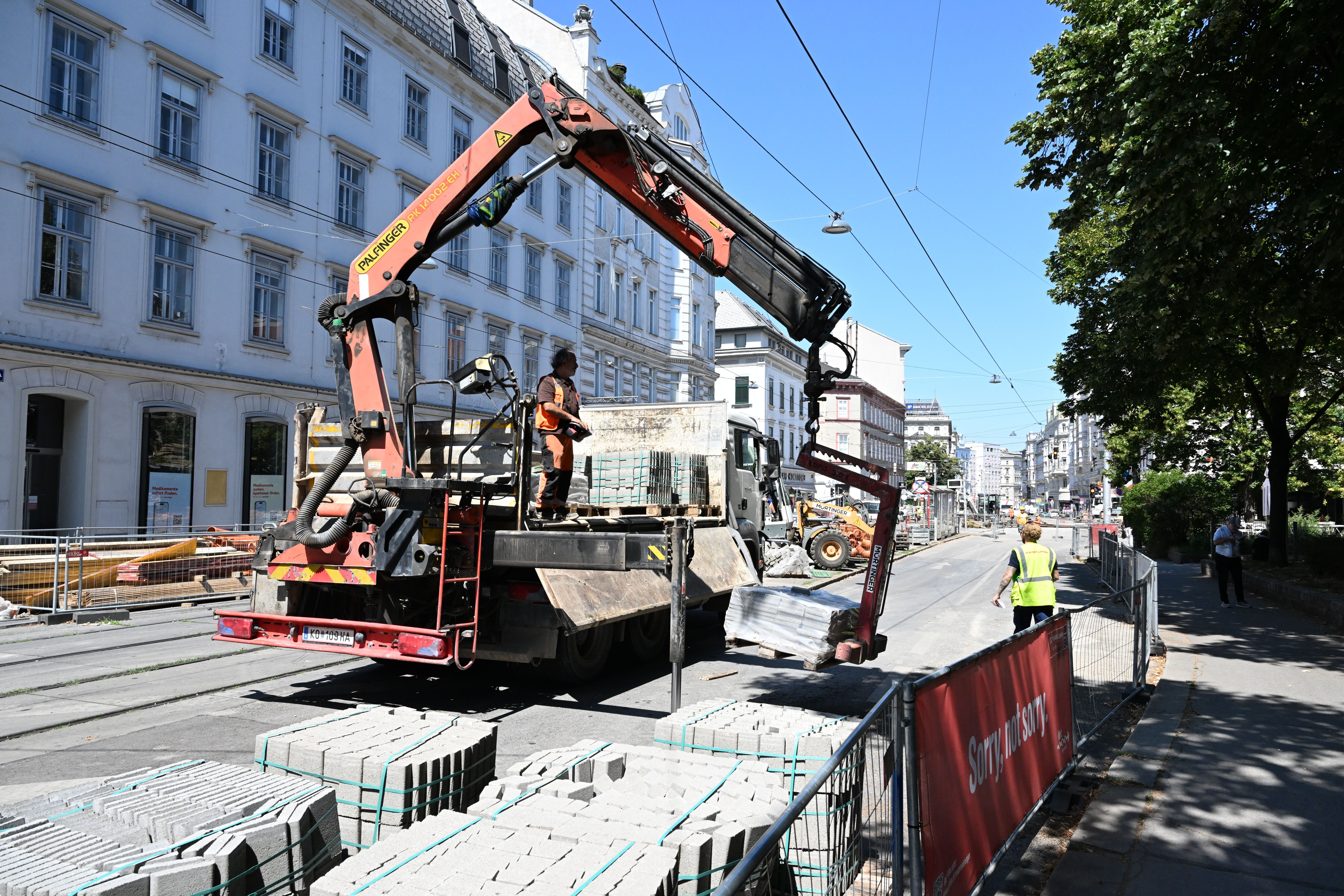 Ein LKW mit Kran entlädt Pflastersteine auf einer Baustelle in der Spitalgasse.
