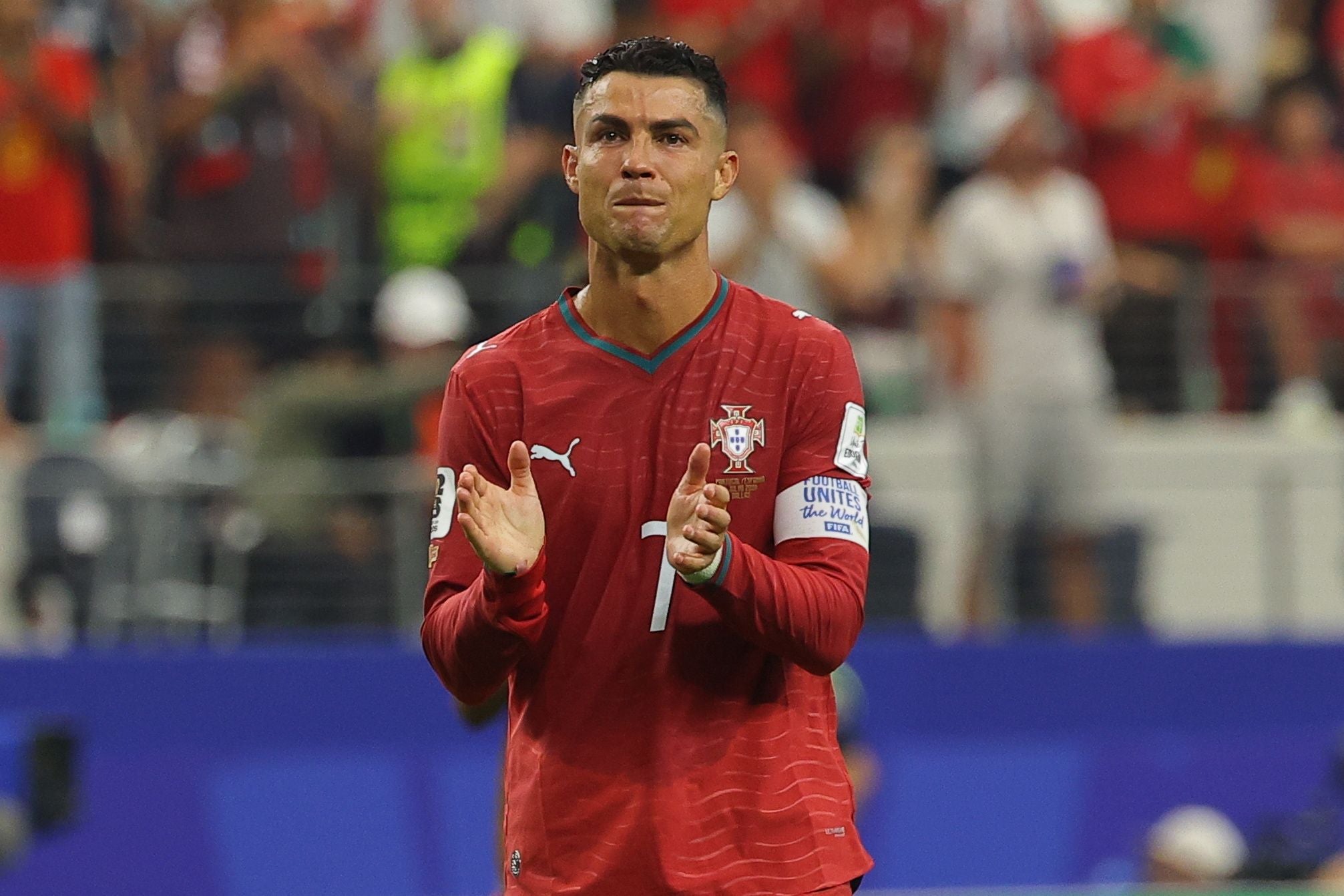Ein portugiesischer Fußballspieler im roten Trikot klatscht enttäuscht nach einem Spiel.