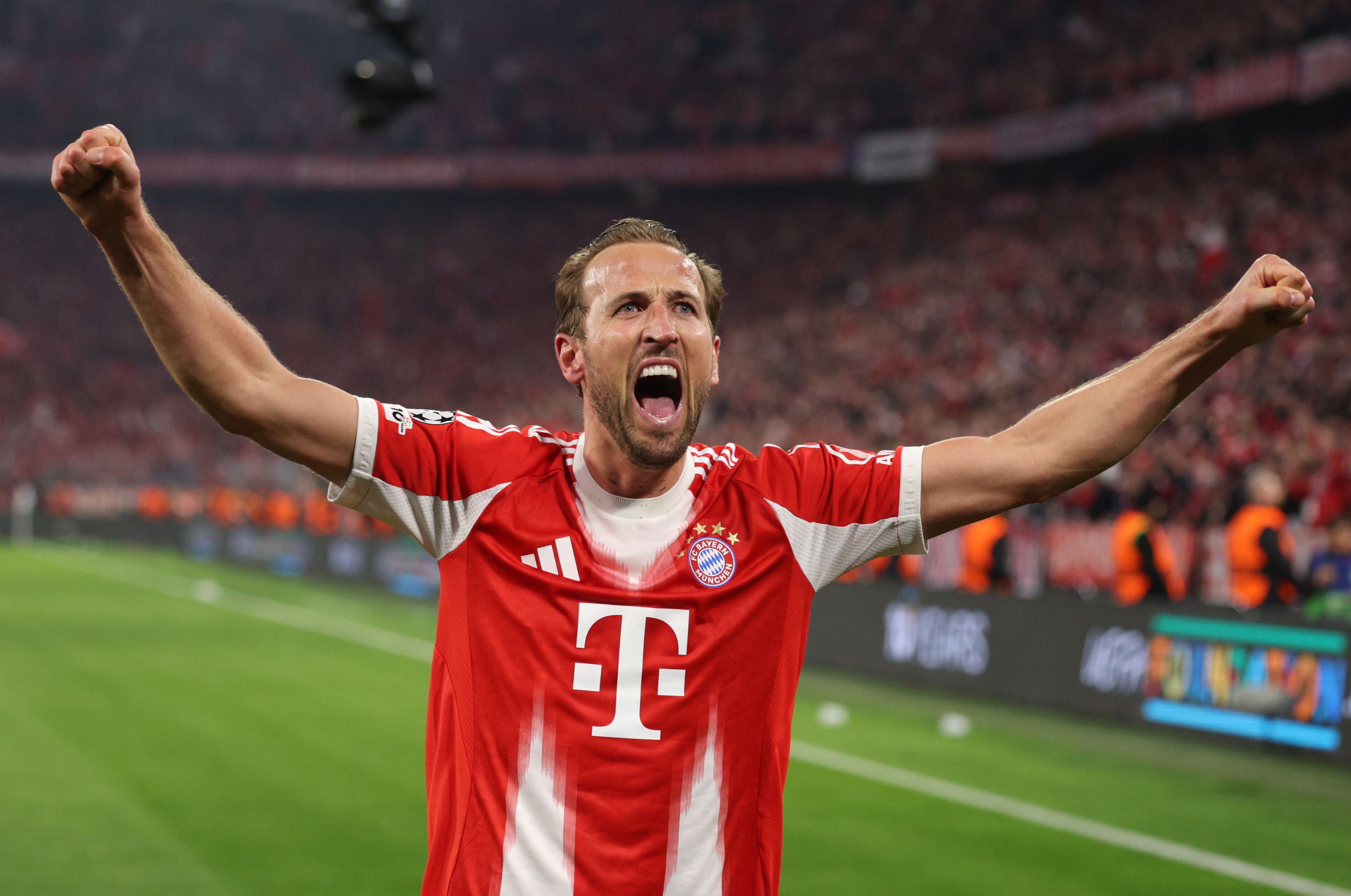 Ein jubelnder Fußballspieler im roten Trikot des FC Bayern München mit erhobenen Armen im Stadion.
