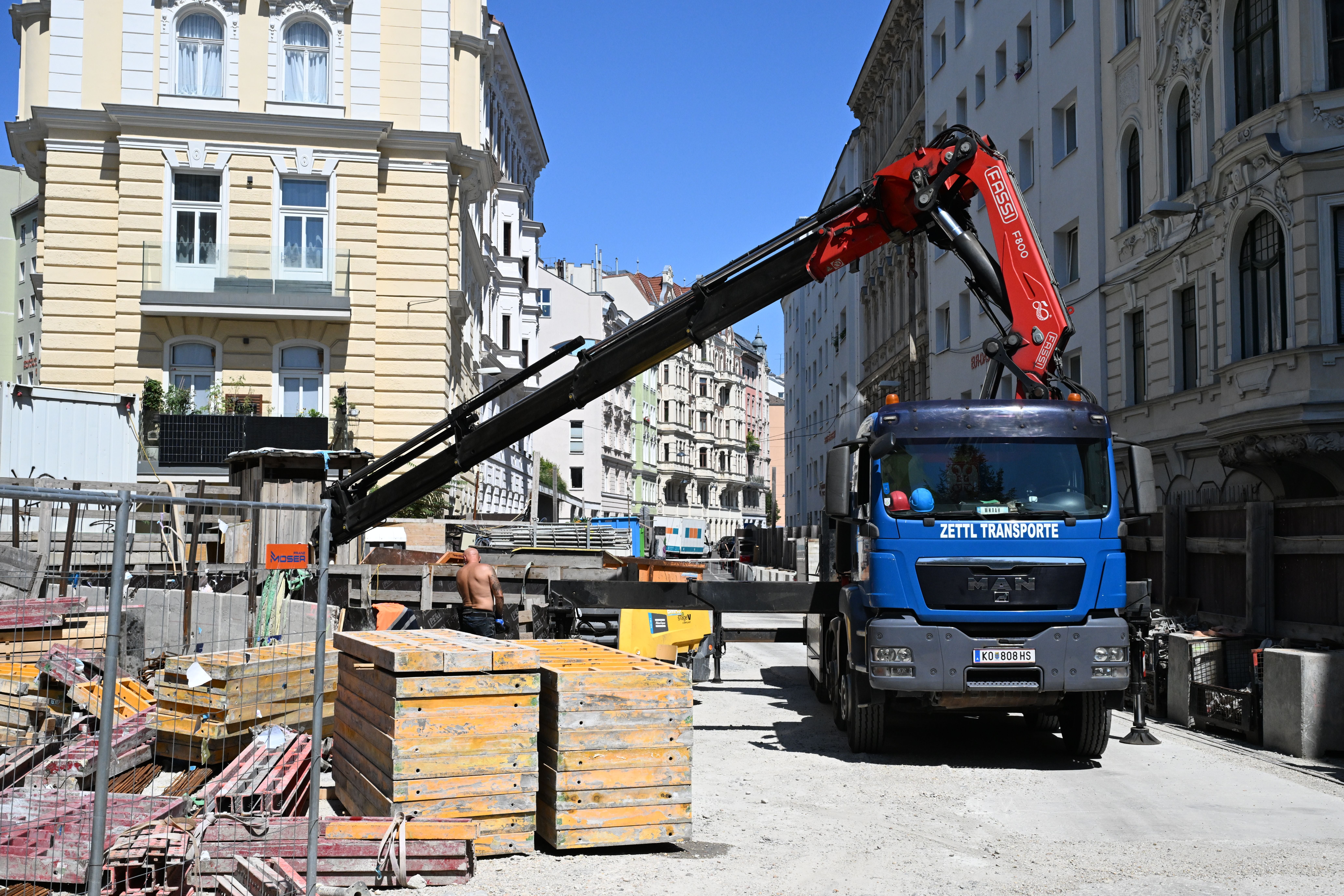 Baustelle mit Kran-LKW und Baumaterialien in der Kaunitzgasse an einem sonnigen Tag.
