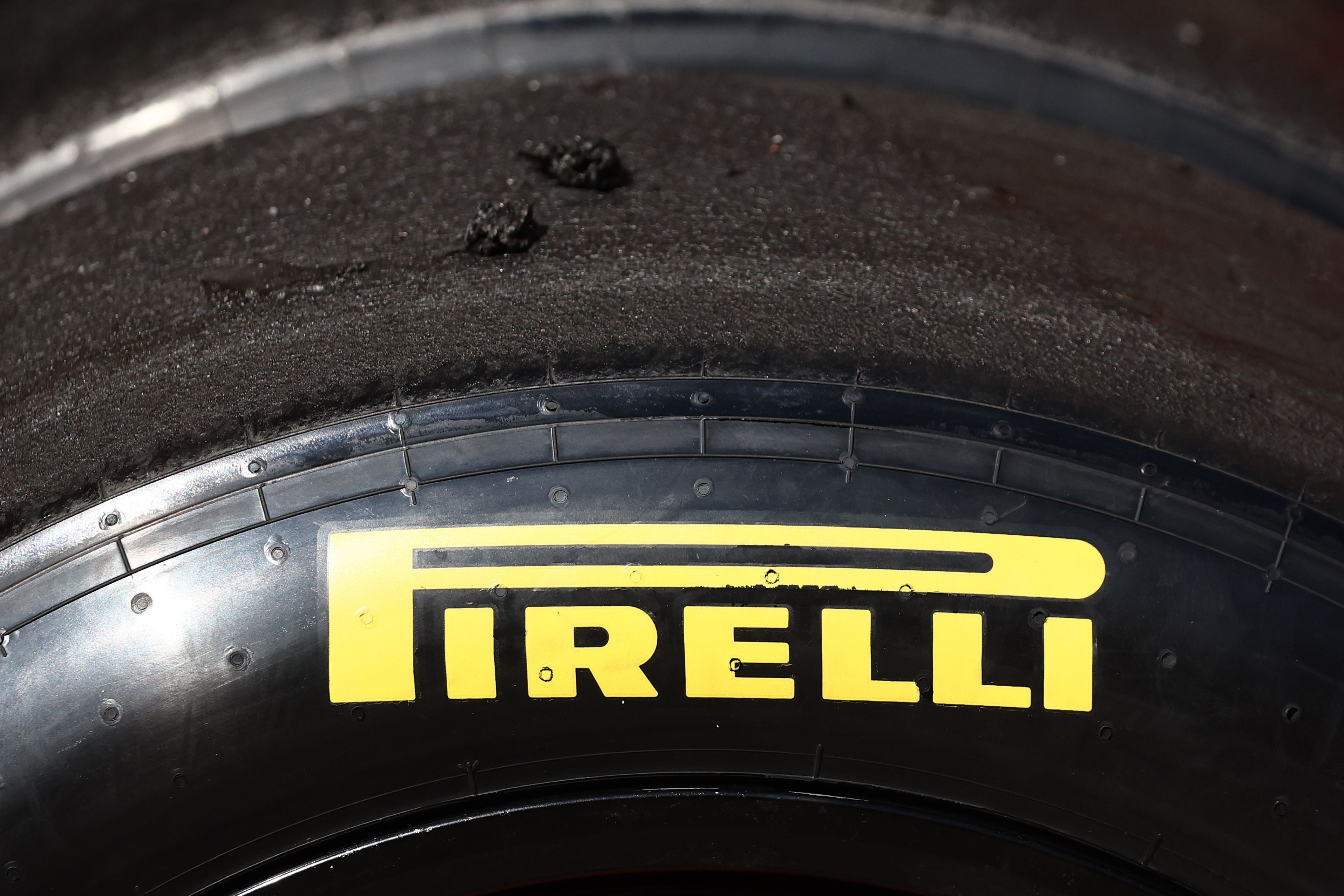 Nahaufnahme eines Pirelli-Rennreifens mit gelbem Logo und abgenutztem Gummi.