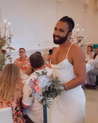 Person im weißen Brautkleid hält einen Blumenstrauß auf einer festlichen Veranstaltung.