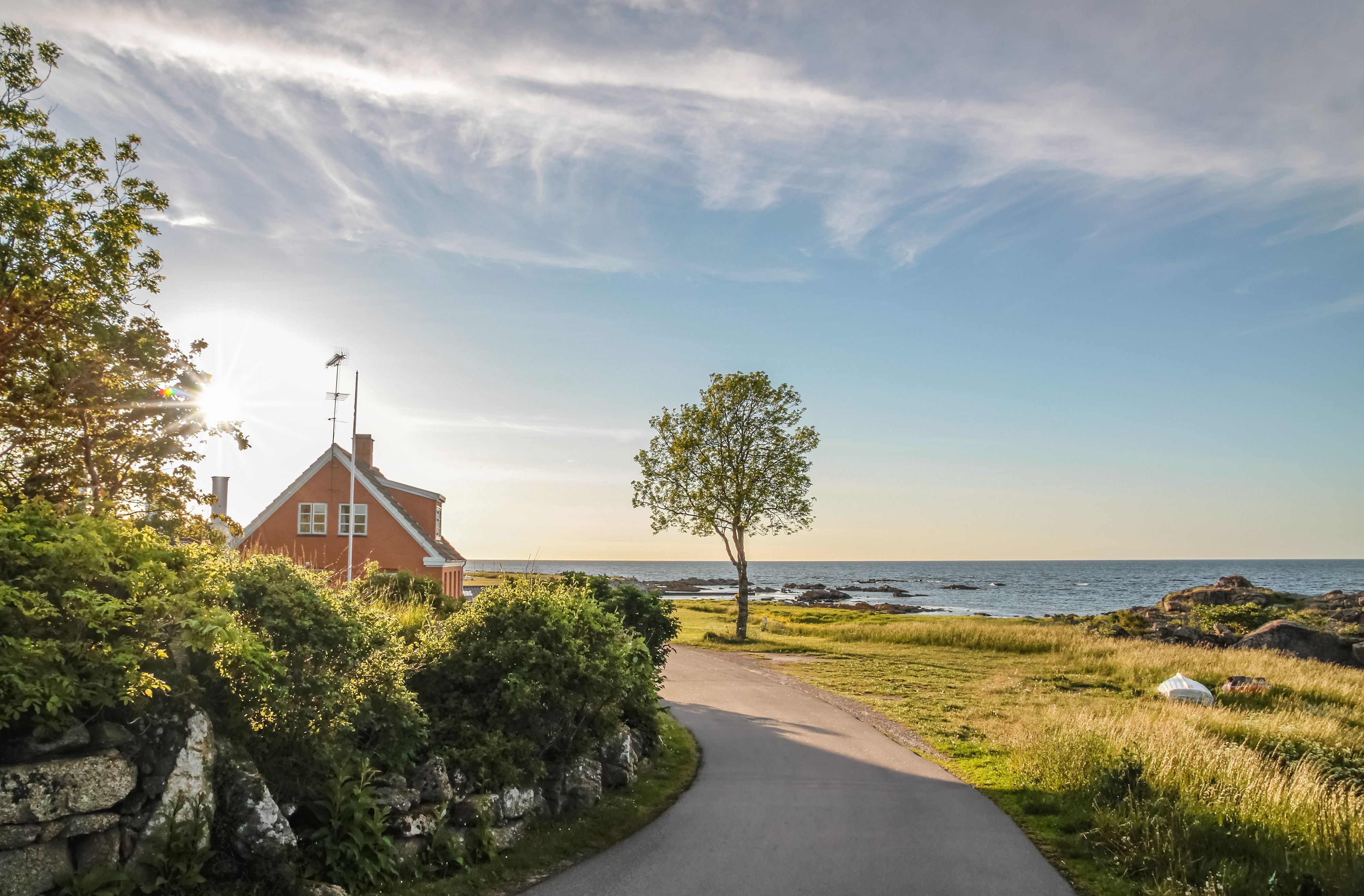 Küstenstraße mit Haus, Baum und Blick aufs Meer bei Listed, Bornholm, Dänemark.