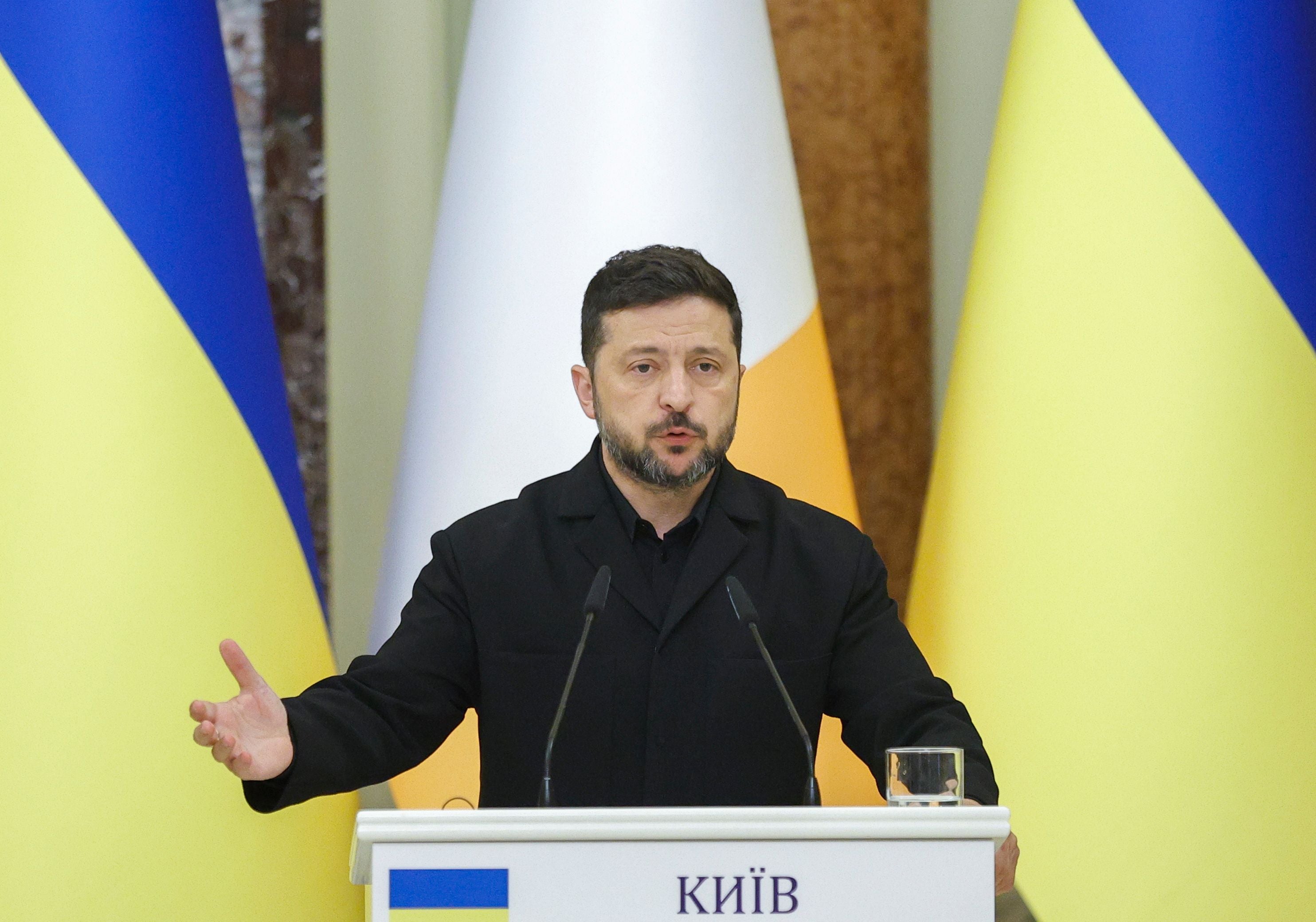 Ein Mann spricht bei einer Pressekonferenz in Kyjiw vor ukrainischen Flaggen und Mikrofonen.