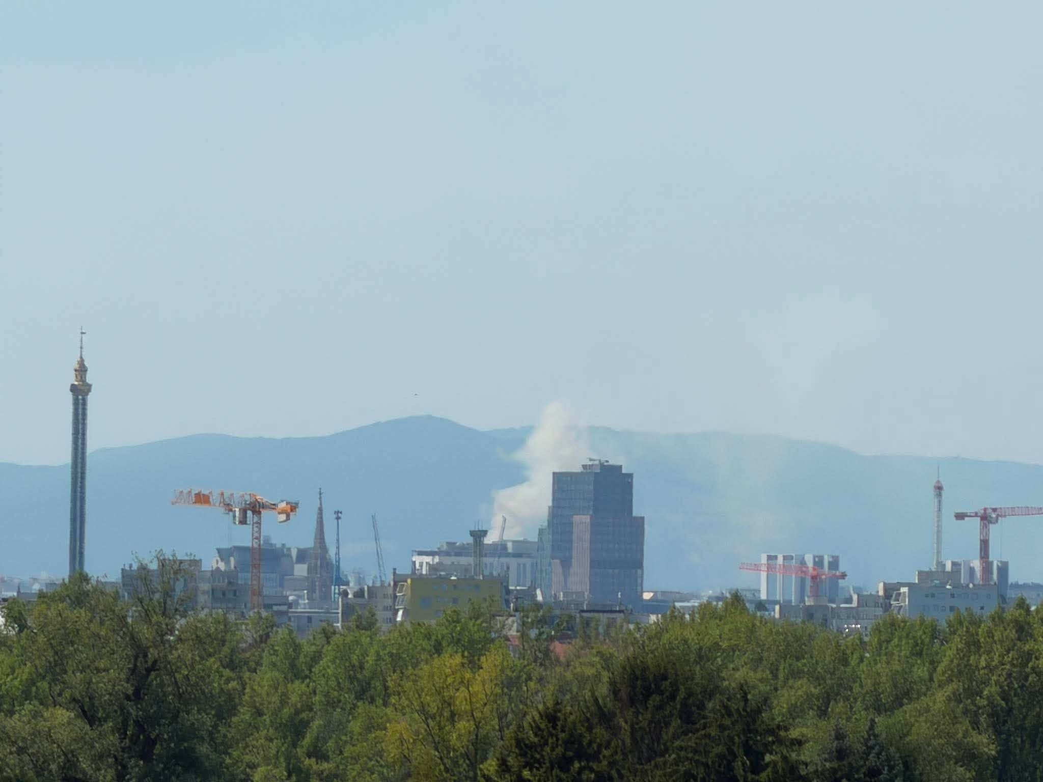 Rauch steigt von einem Gebäude in Meidling über der Stadt und vor Hügeln auf.