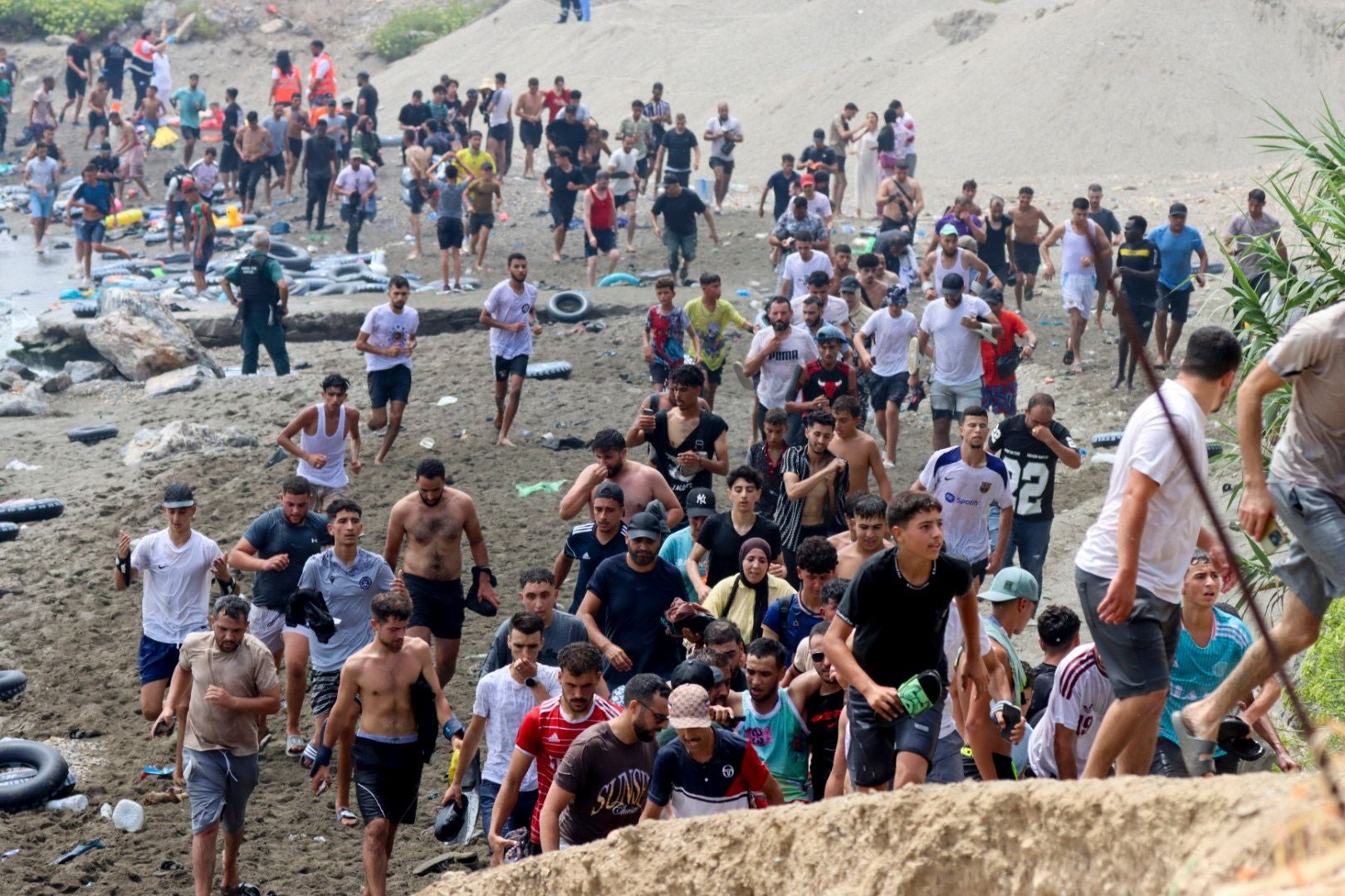 Viele Menschen laufen erschöpft am Strand, nachdem sie anscheinend das Wasser durchquert haben.
