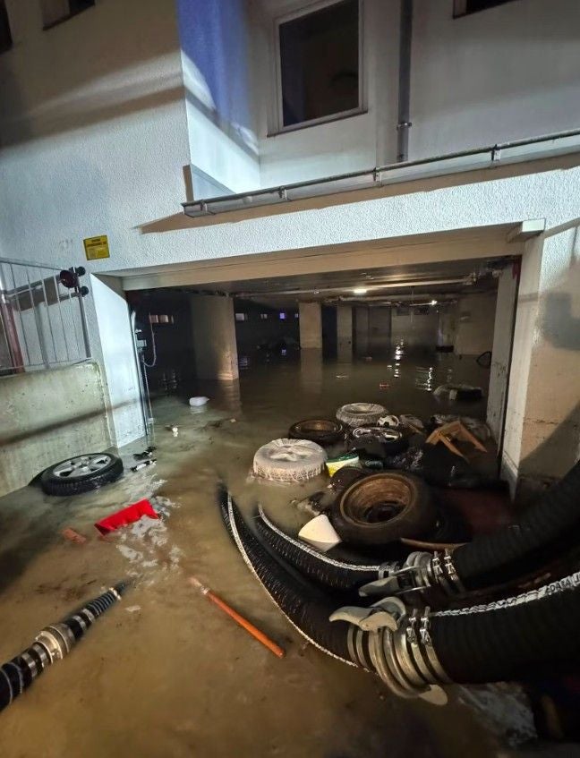 Überflutete Tiefgarage in Tirol mit Autoreifen, Müll und Schläuchen im Wasser.
