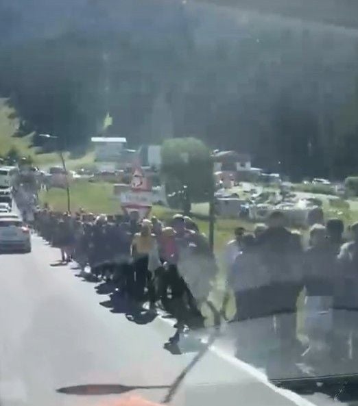 Eine große Menschenmenge wandert auf einer Straße in Richtung Drei Zinnen in den Alpen.