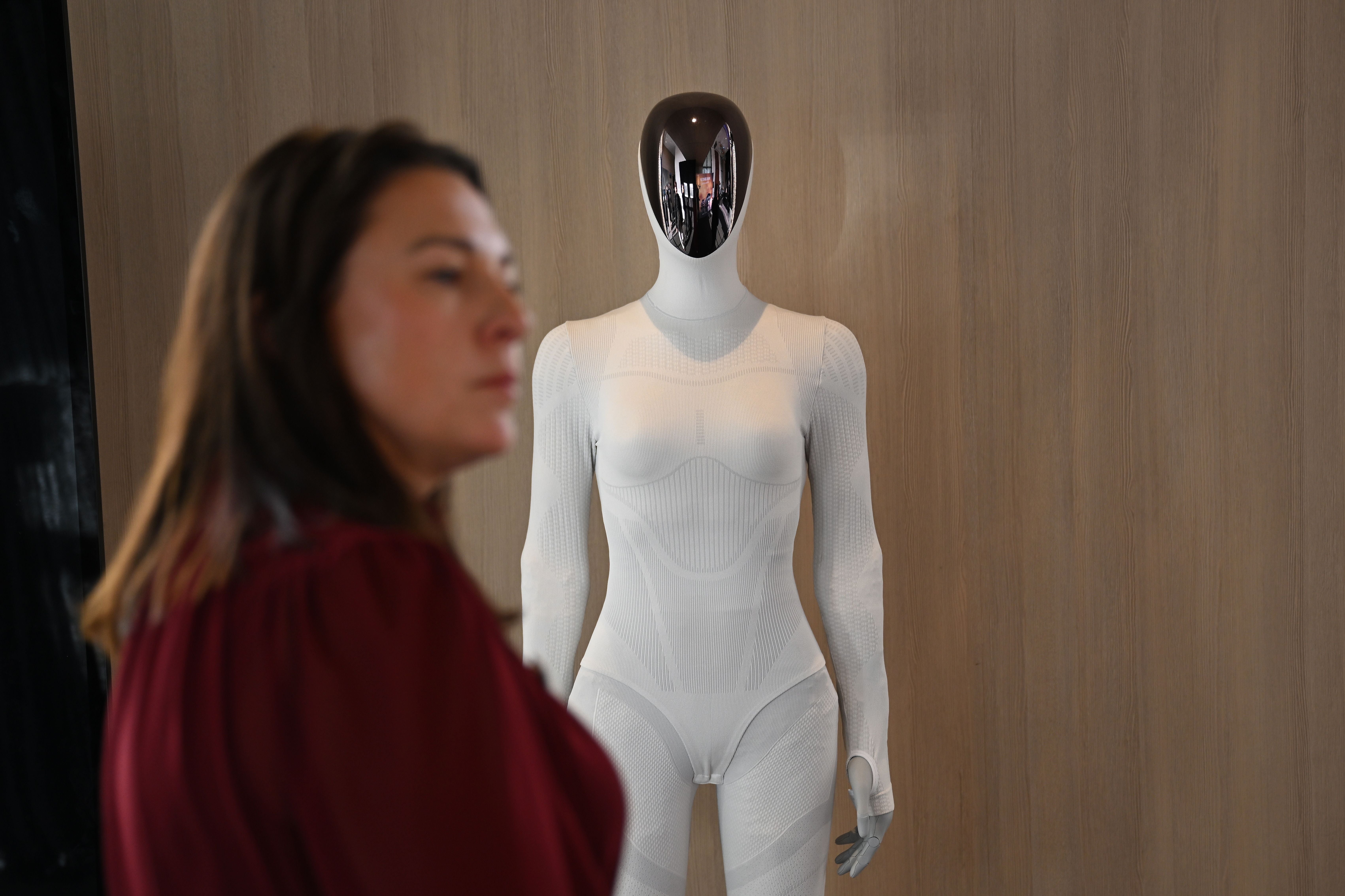 Eine XPeng Iron Humanoid-Roboterfigur steht bei einer Veranstaltung, vorne eine Frau unscharf.