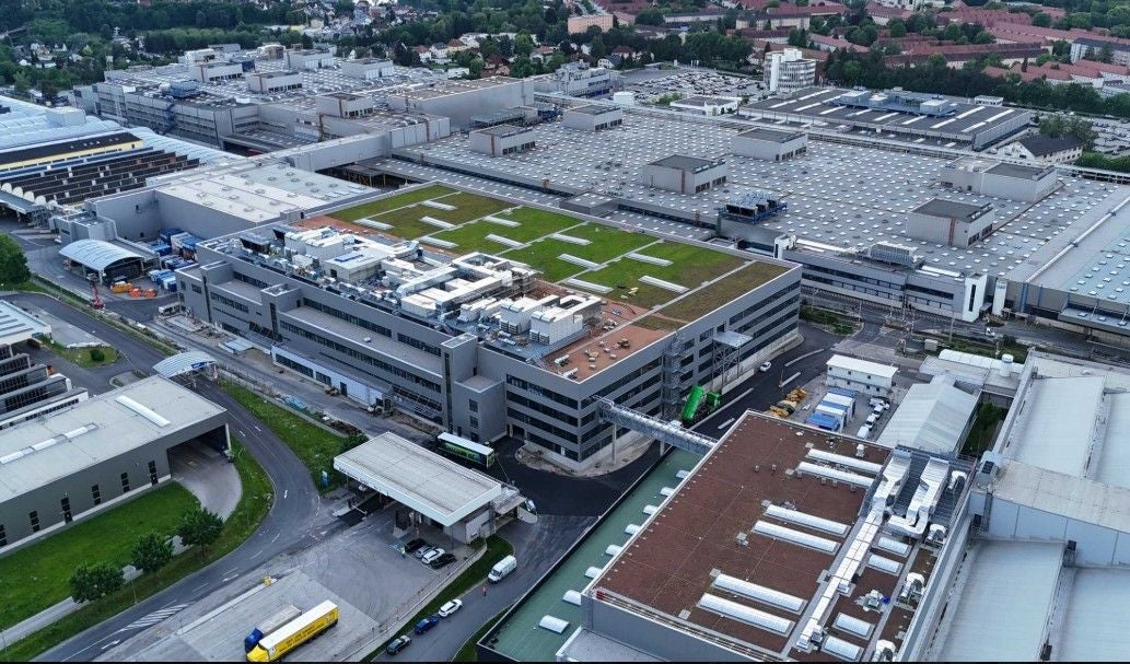 Luftaufnahme eines großen Industriekomplexes mit begrünten Flachdächern in Steyr.