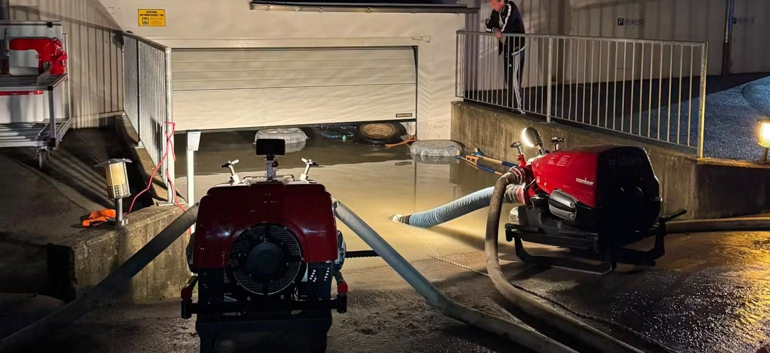 Zwei Pumpen entwässern eine überflutete Tiefgarageneinfahrt bei Nacht in Tirol.