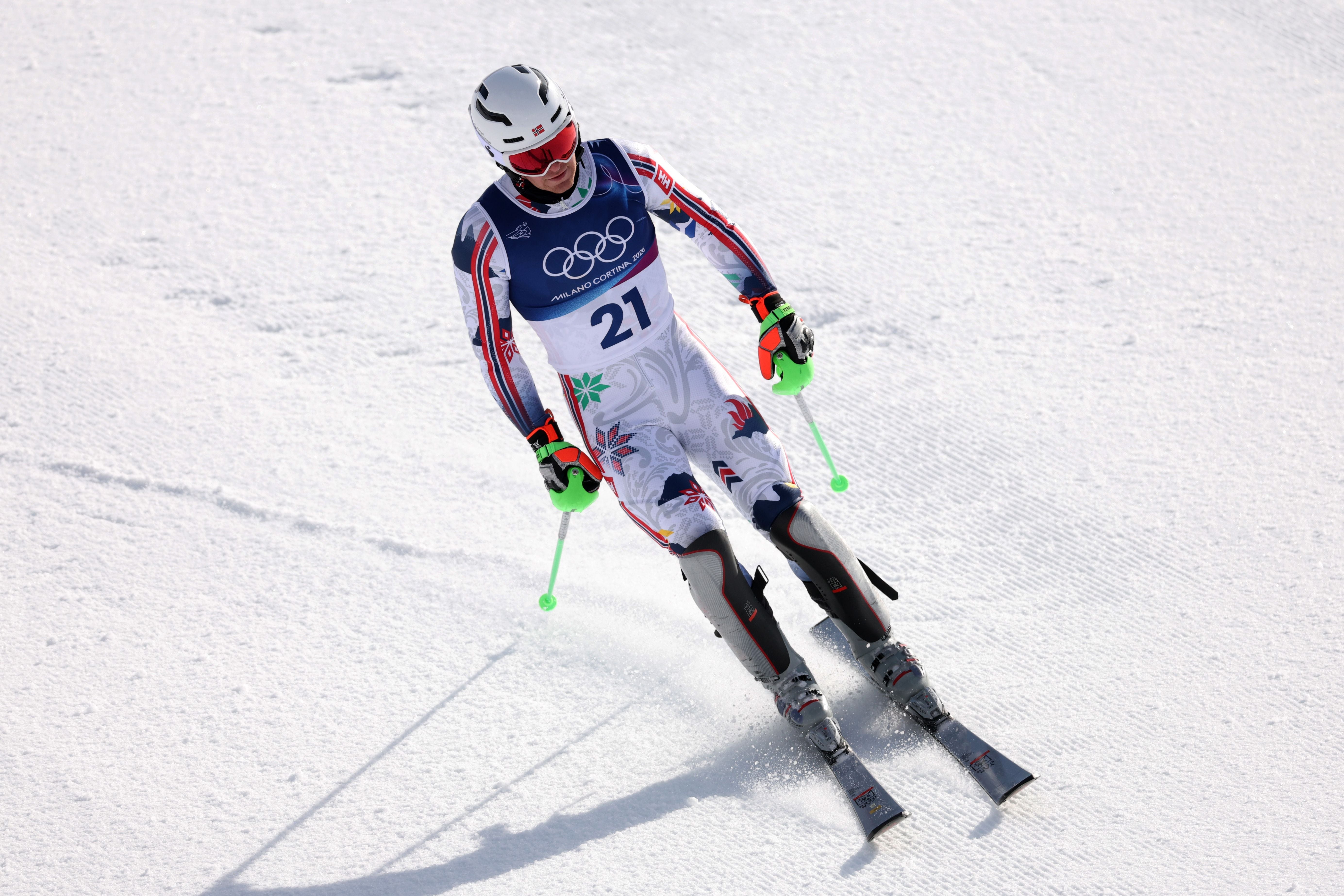 Ein Skirennläufer überquert die Ziellinie bei einem olympischen Slalom-Rennen im Schnee.