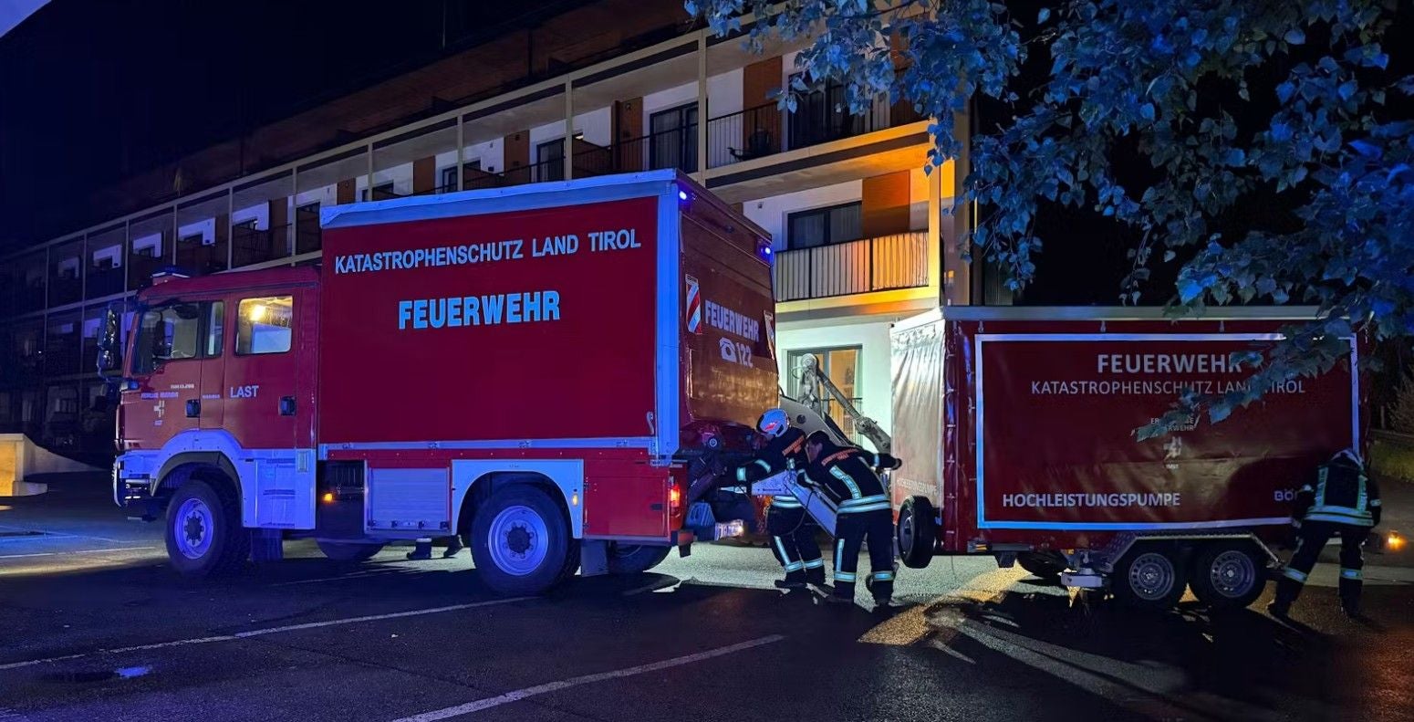 Feuerwehrleute arbeiten nachts an Einsatzfahrzeugen des Katastrophenschutzes in Tirol.
