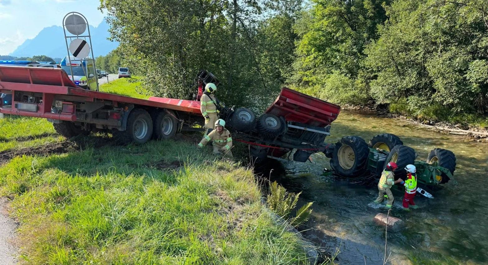 Einsatzkräfte bergen einen umgestürzten Traktor aus der Tiroler Ache bei einem Verkehrsunfall.