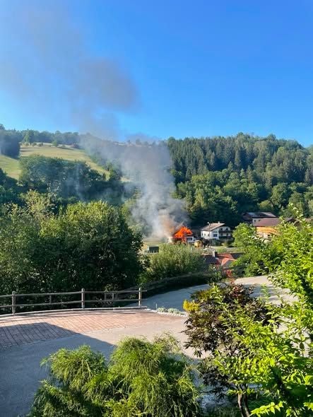 Ein Haus in Frankenfels steht in Flammen, Rauch steigt vor bewaldetem Hügel auf.