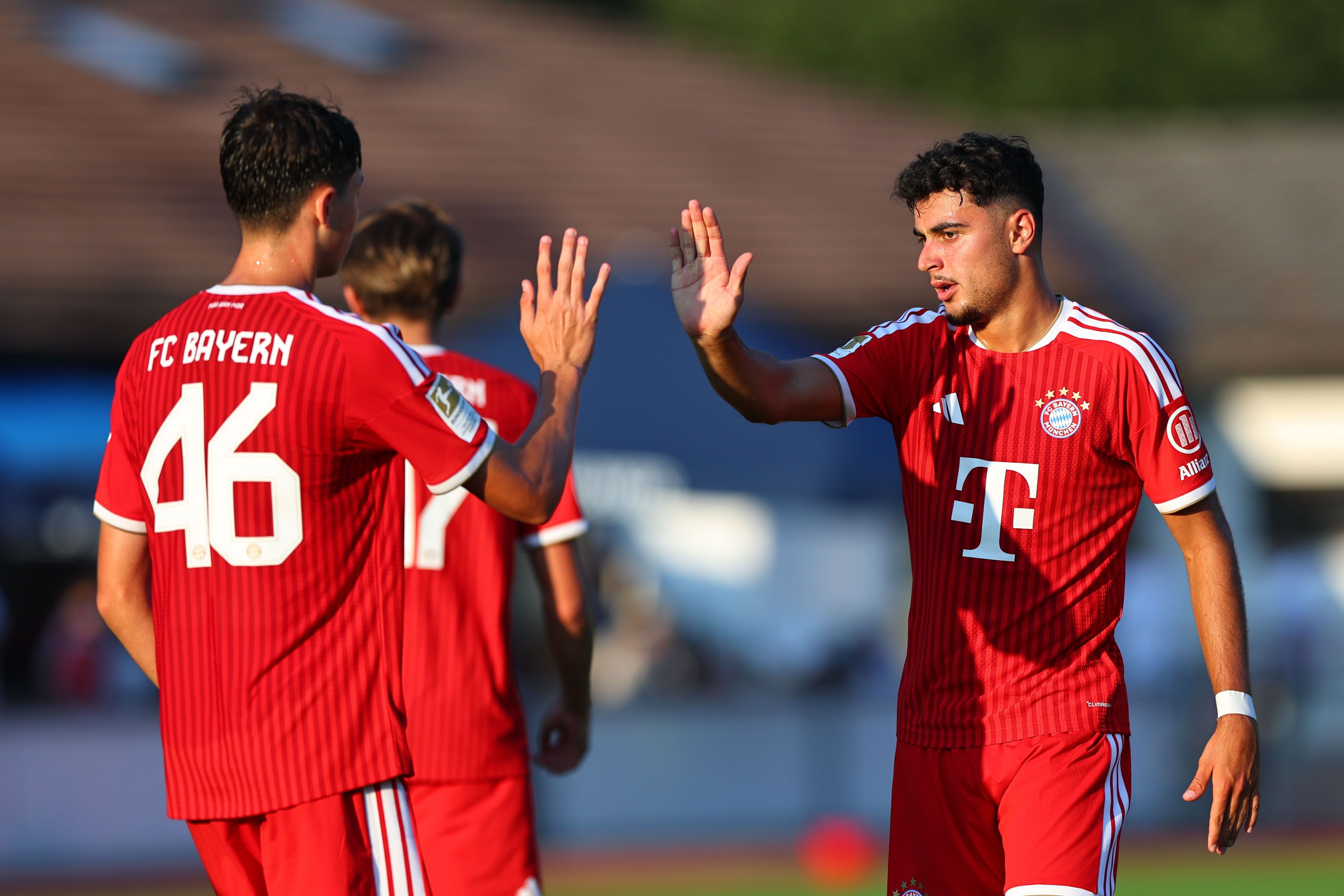 Zwei Bayern-Spieler klatschen sich auf dem Fußballplatz während eines Spiels ab.