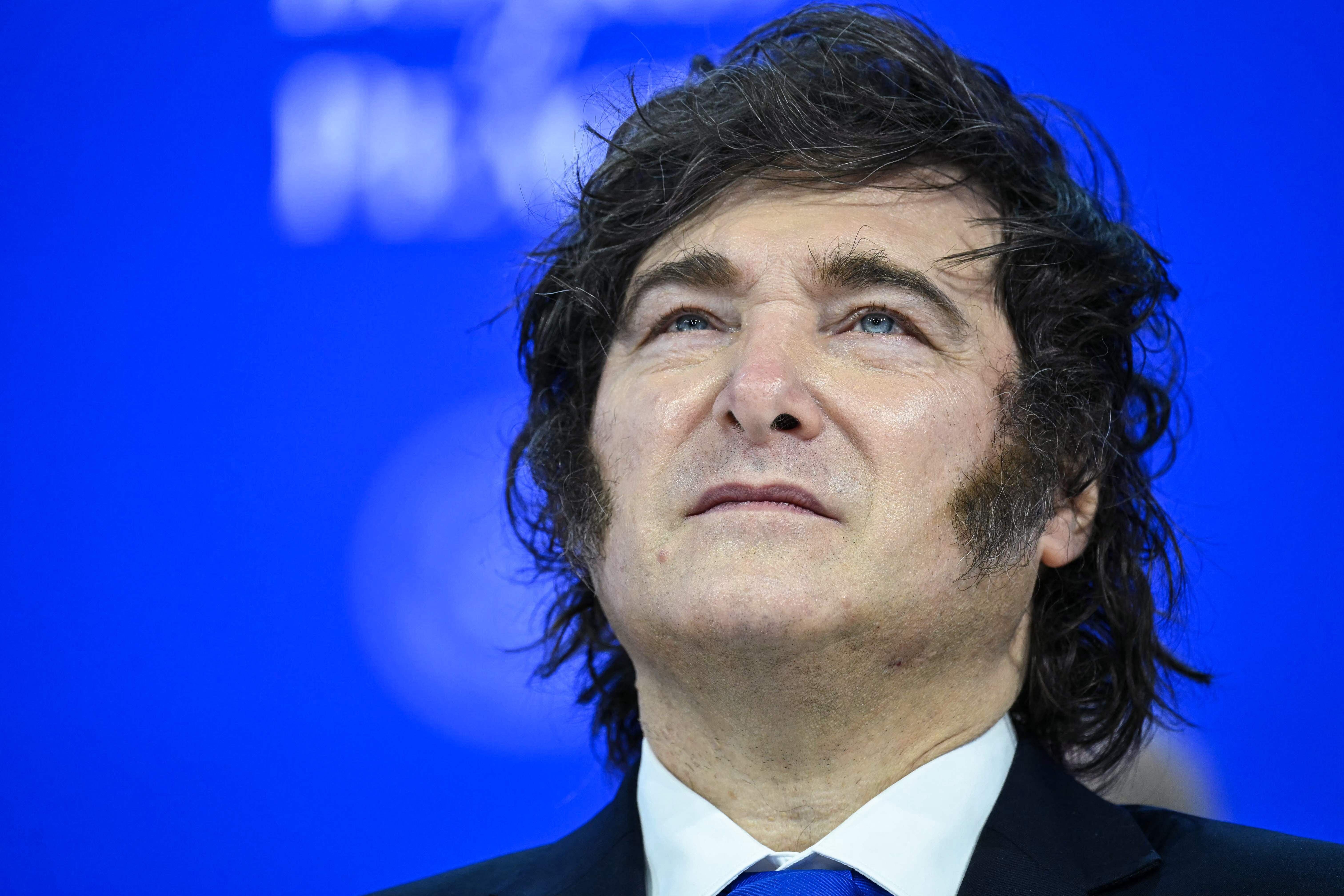 Ein Mann im Anzug blickt ernst nach oben vor blauem Hintergrund.