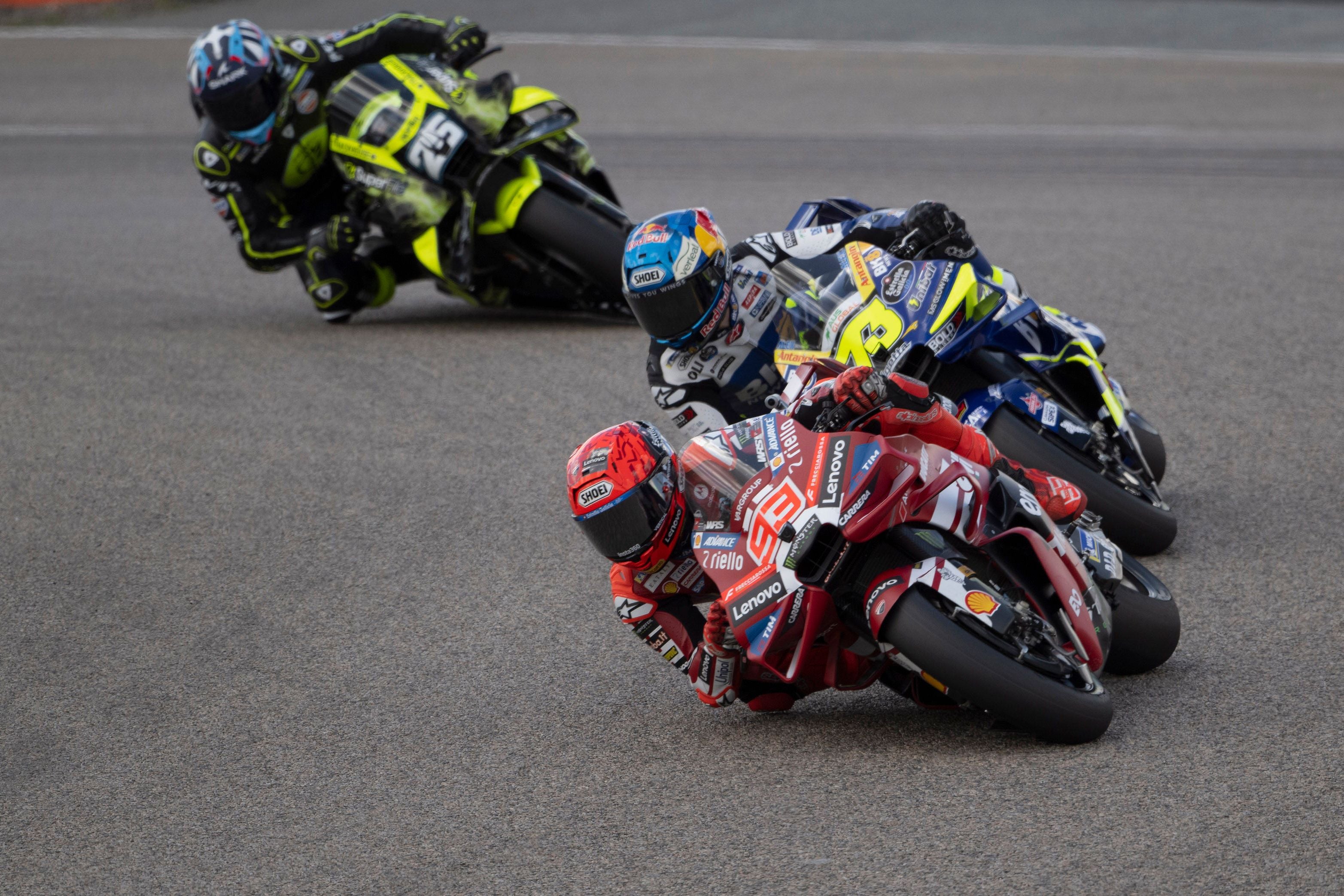 Drei Motorradrennfahrer lehnen sich in einer Kurve während eines MotoGP-Rennens auf dem Sachsenring.