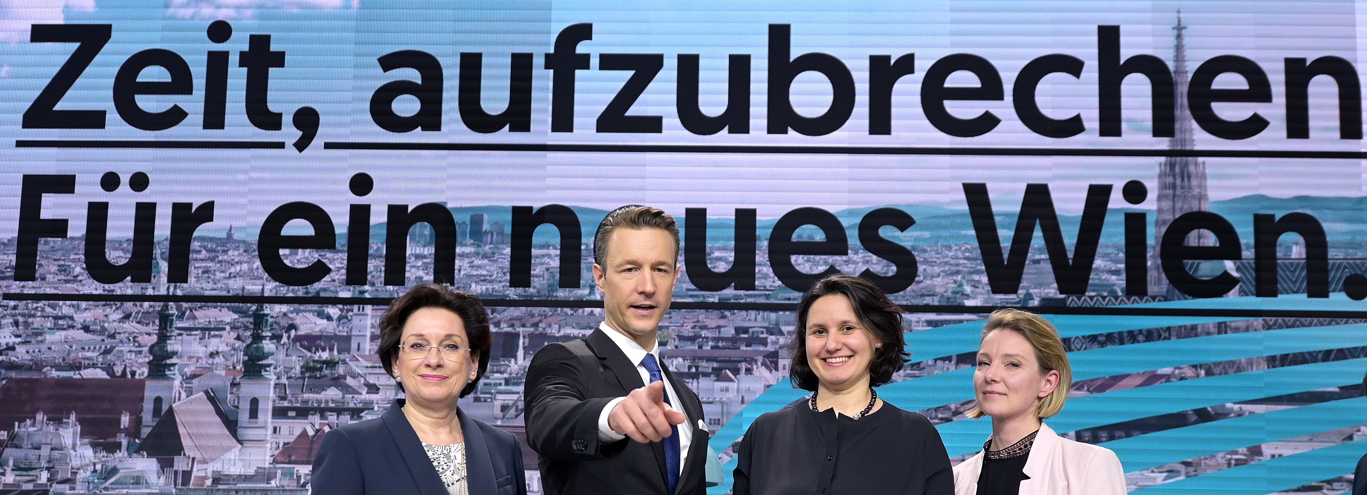 Vier Personen posieren vor einer Leinwand mit dem Text „Zeit, aufzubrechen. Für ein neues Wien.“