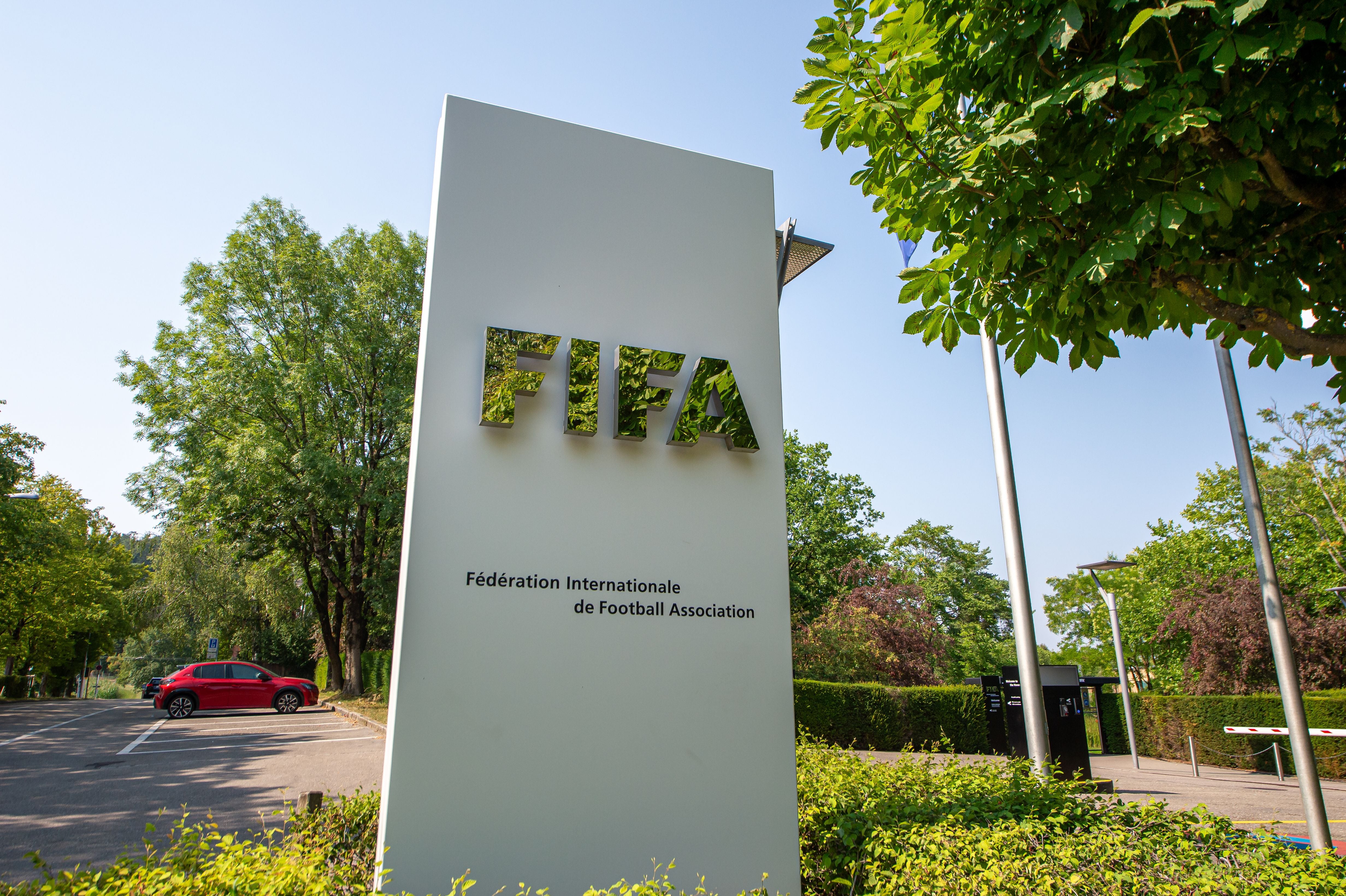 Großes FIFA-Schild vor dem Hauptquartier in Zürich, umgeben von Bäumen und einer Straße.