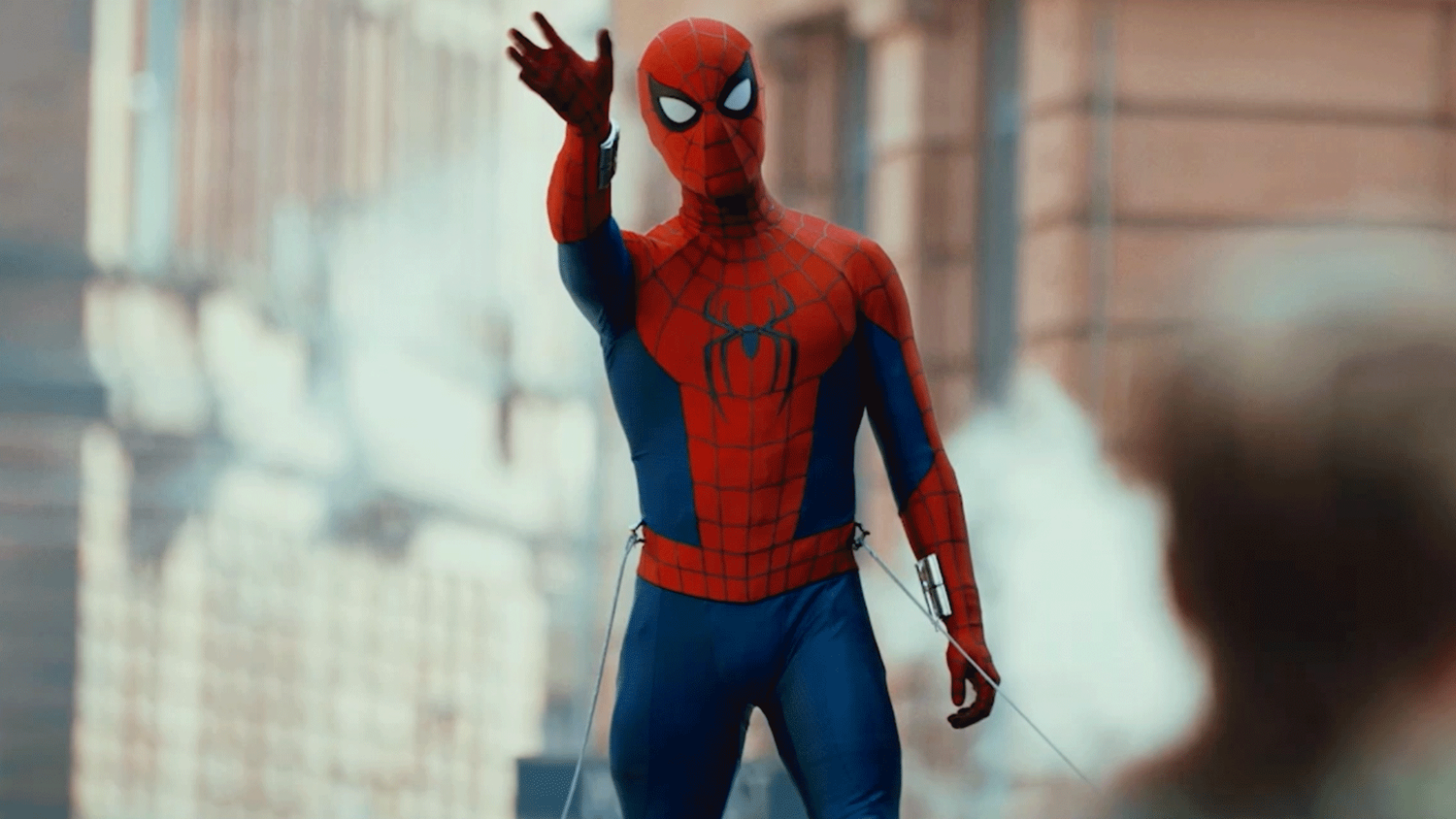 Spider-Man steht mit ausgestrecktem Arm in einer Stadt und blickt nach vorne.