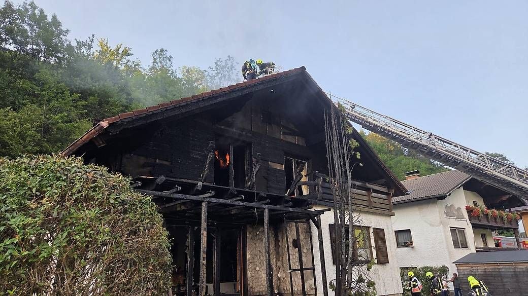 Verbranntes Wohnhaus mit Rauch, Feuerwehrleute löschen Brand am Dach in Frankenfels.
