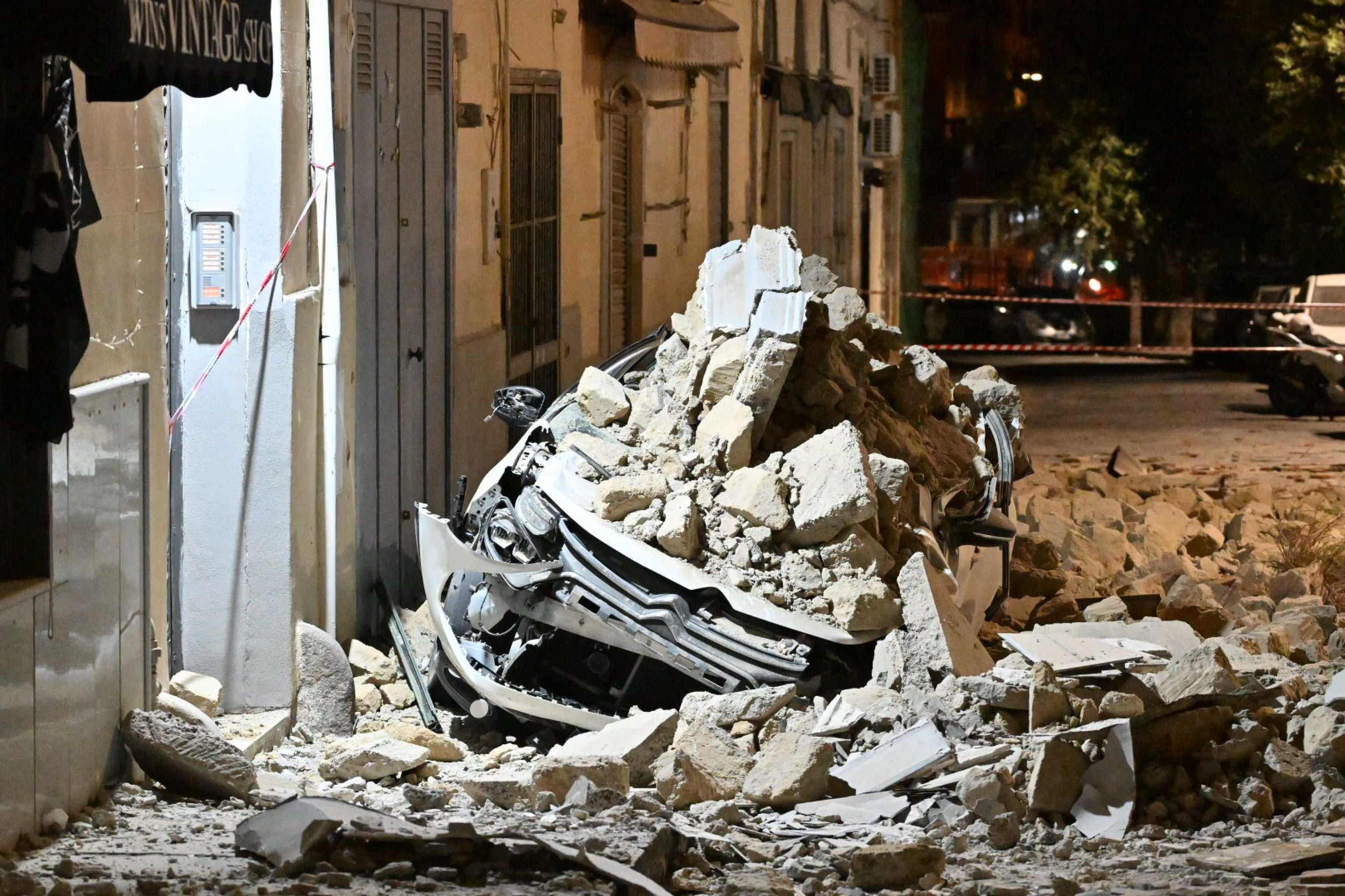 Ein Auto ist von herabgefallenen Trümmern eines Gebäudes nach einem Erdbeben bedeckt.