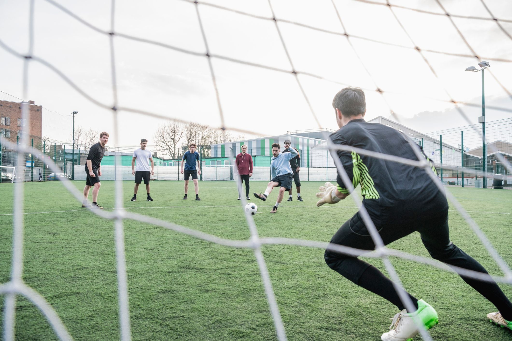 Ein Spieler schießt auf ein Fußballtor, der Torwart ist zum Abwehren bereit.