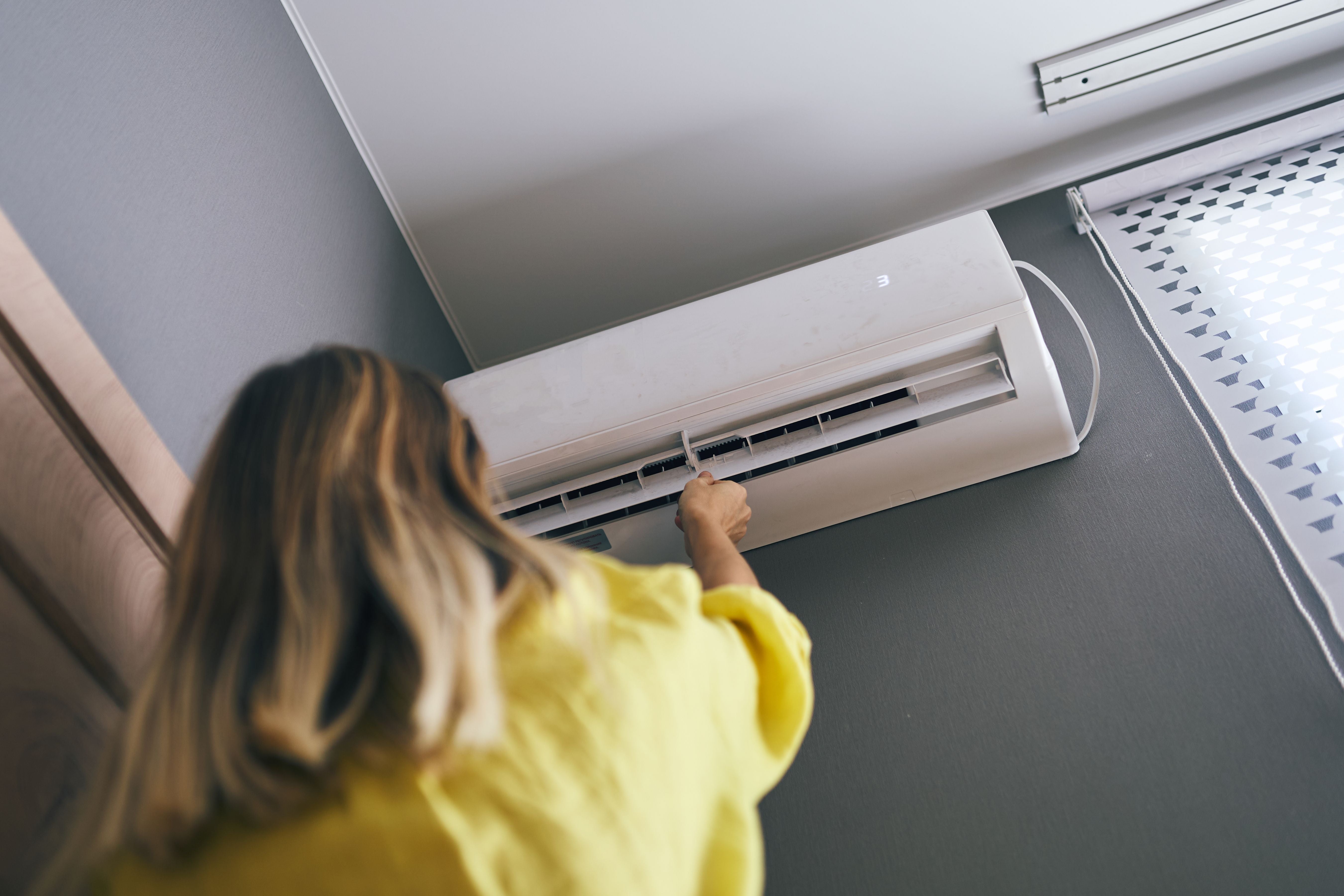 Frau stellt eine Klimaanlage an der Wand ein.