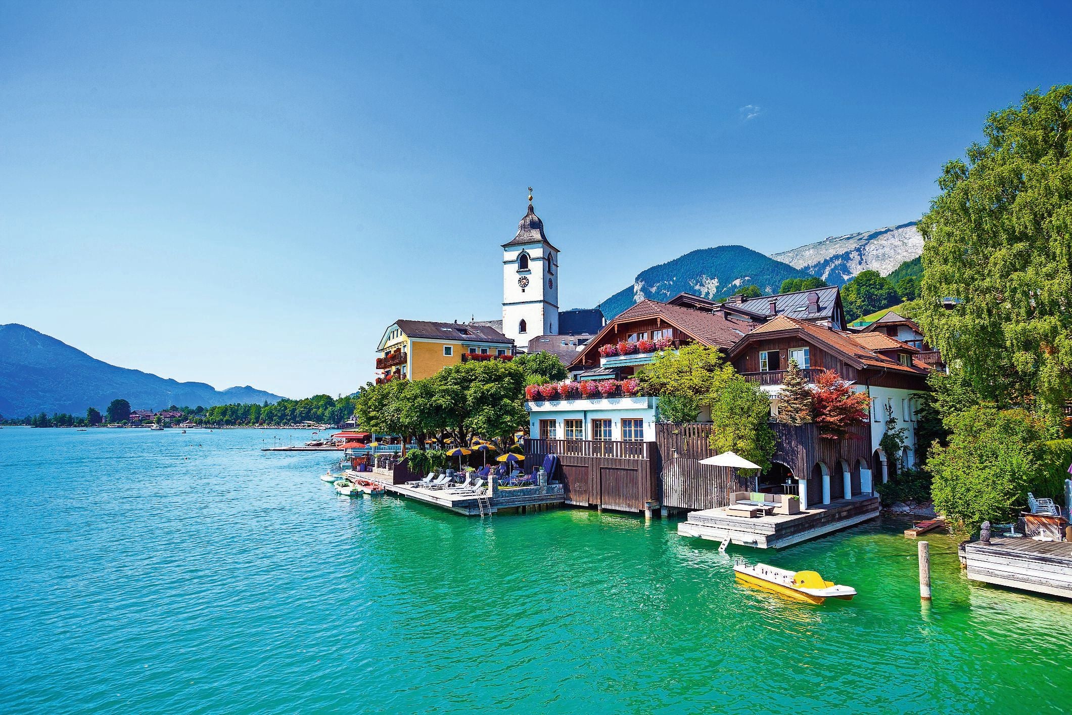 Blick auf St. Wolfgang am Wolfgangsee mit Kirche, bunten Häusern und Bergen im Hintergrund.