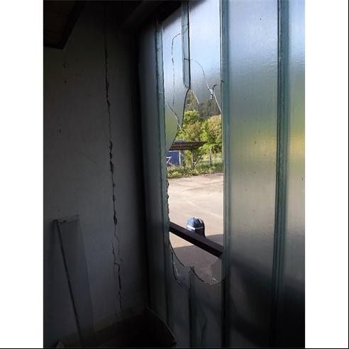 Fensterscheibe mit großem Loch nach einem Einbruch, Blick nach draußen auf die Straße.