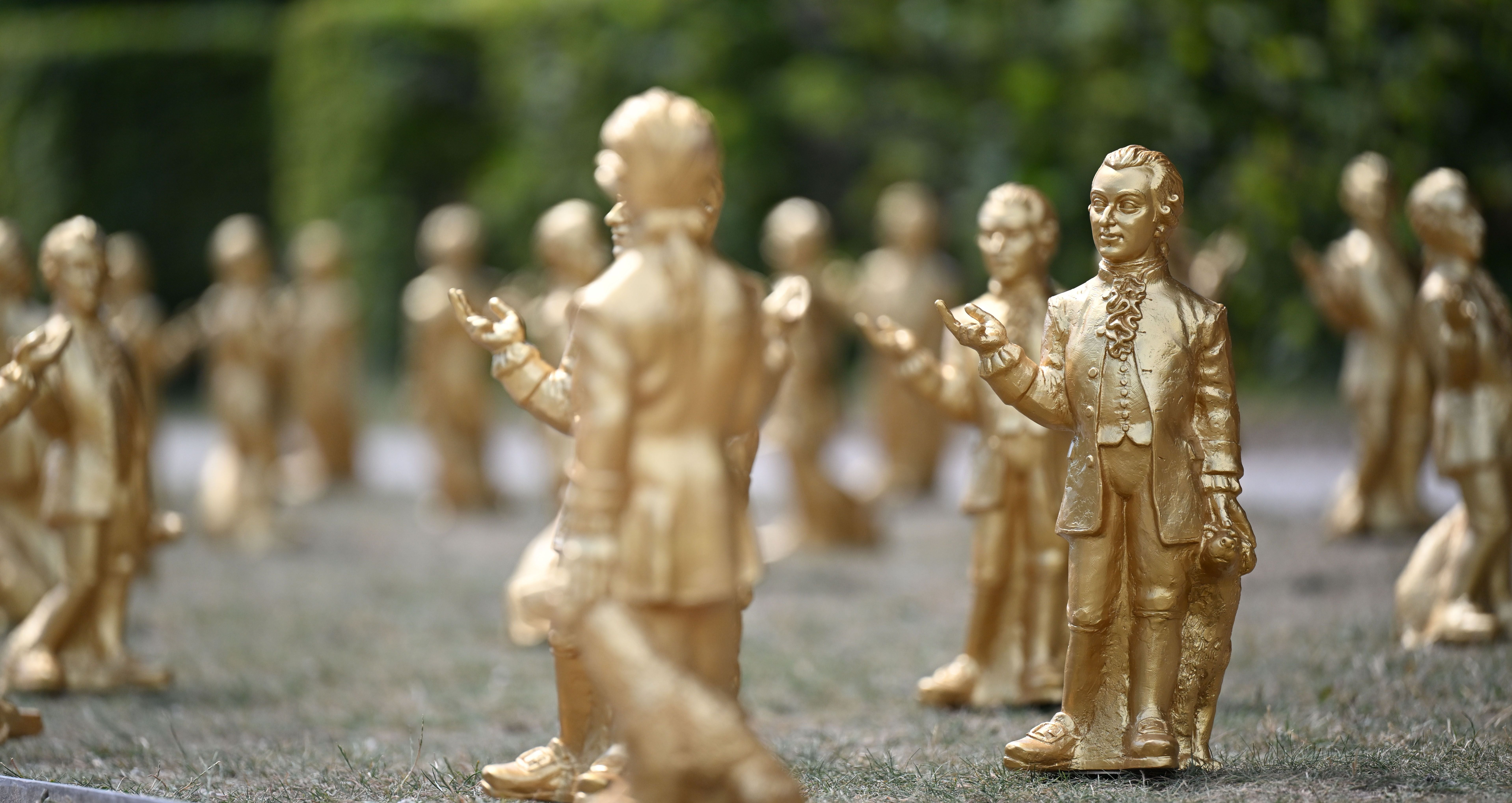 Viele goldene Mozart-Figuren stehen im Freien auf einer Wiese im Mirabellgarten in Salzburg.