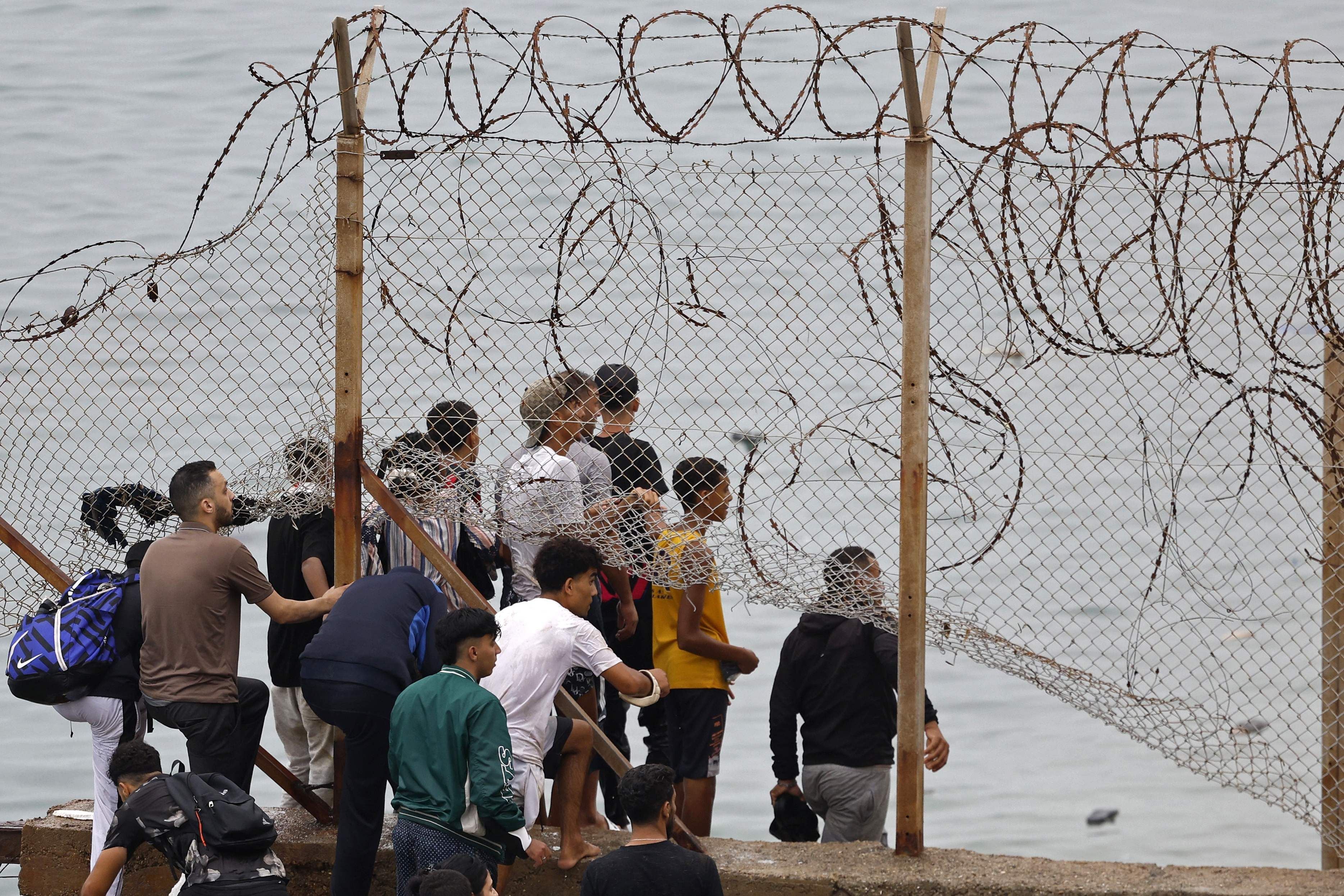 Menschen stehen an einem Stacheldrahtzaun an der marokkanisch-spanischen Grenze bei Ceuta.