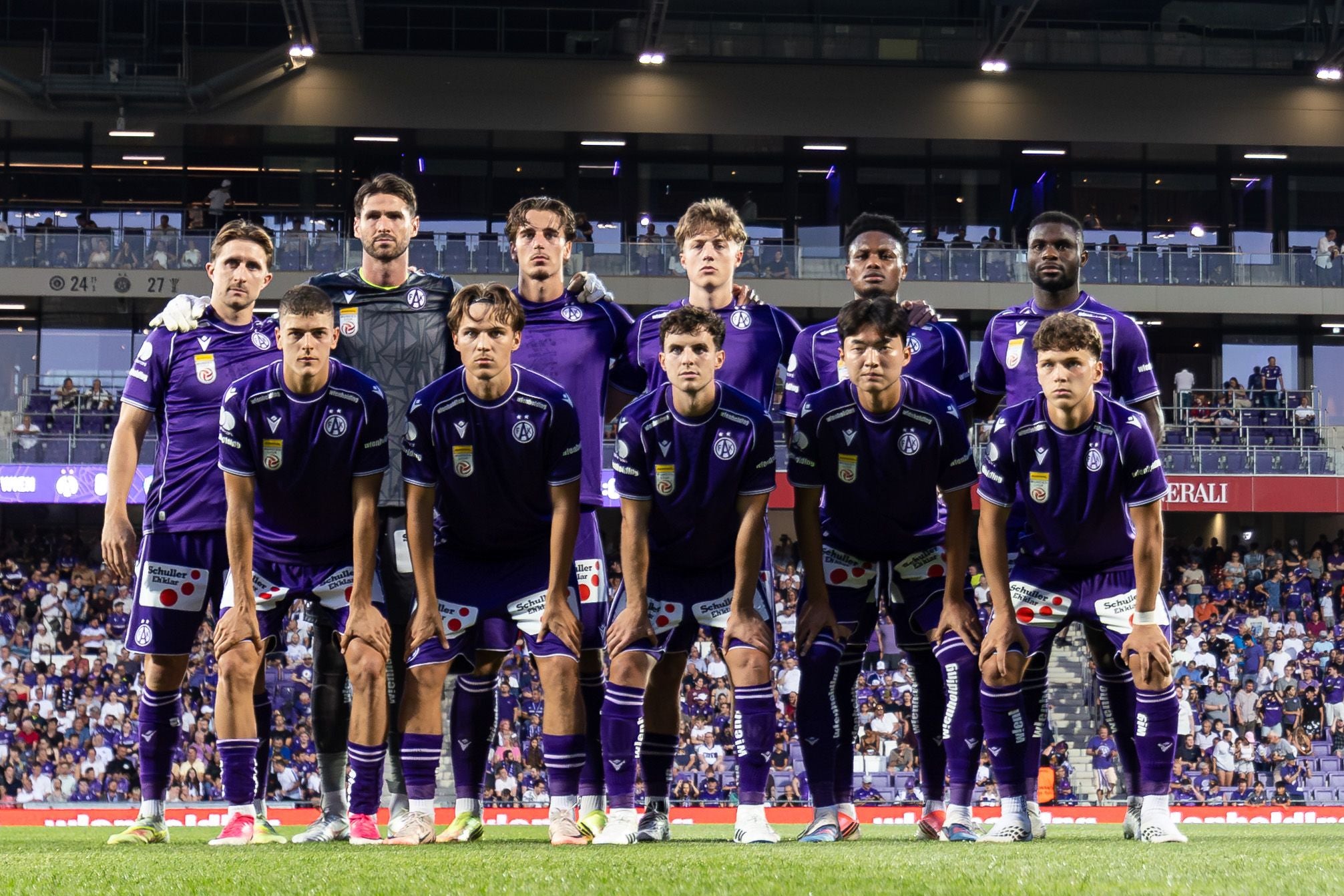 Das Fußballteam von Austria Wien posiert vor einem UEFA Conference League-Spiel im Stadion.