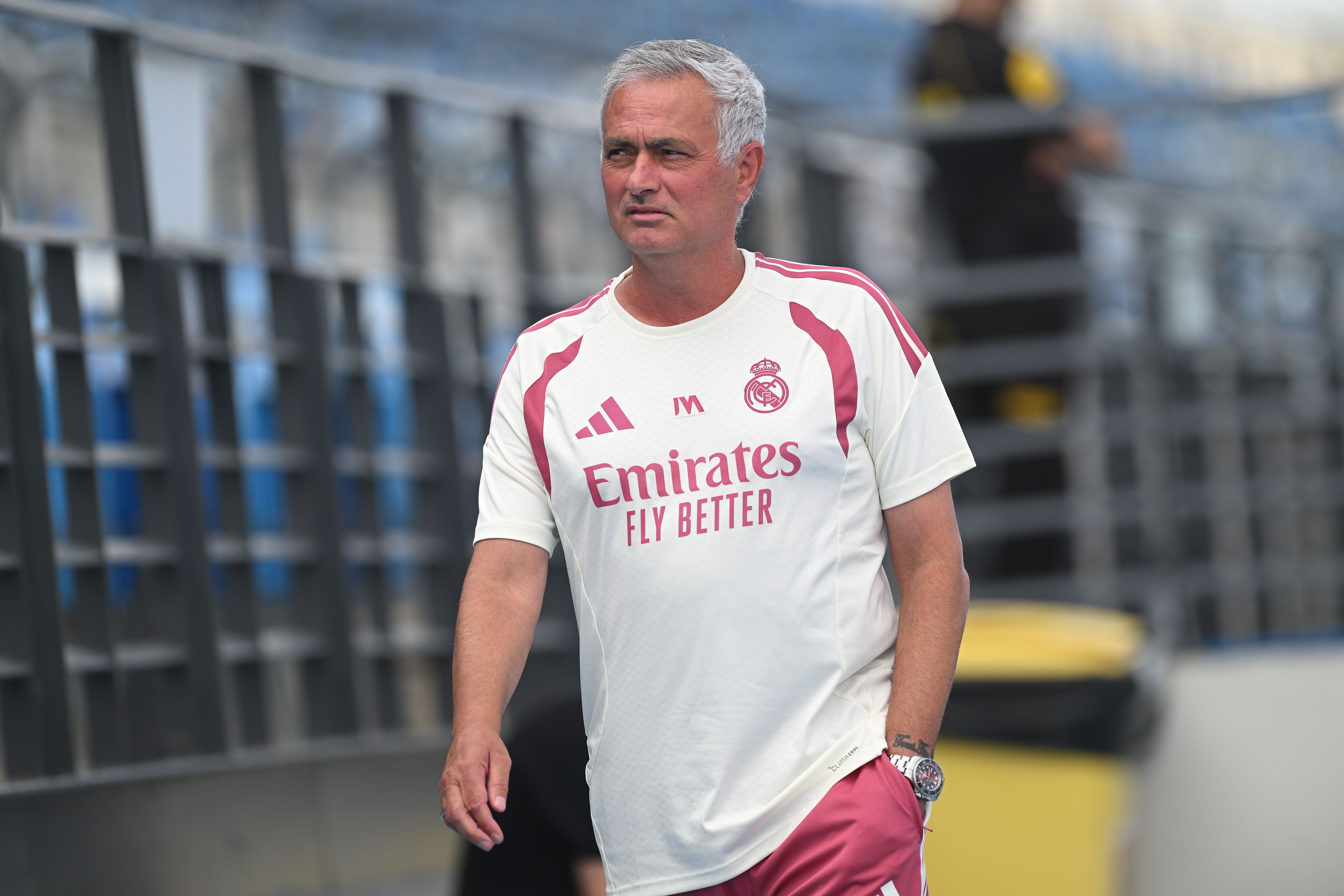Ein Mann im Real Madrid Trainingsanzug steht am Spielfeldrand eines Fußballstadions.