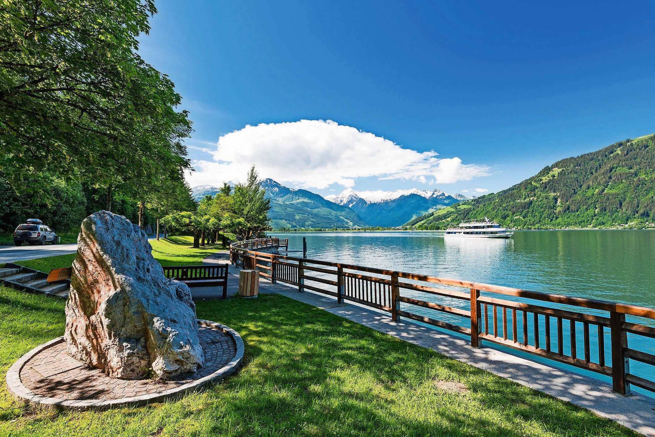 Promenade am Zeller See mit Blick auf eine Fähre und umliegende Berge in Österreich.